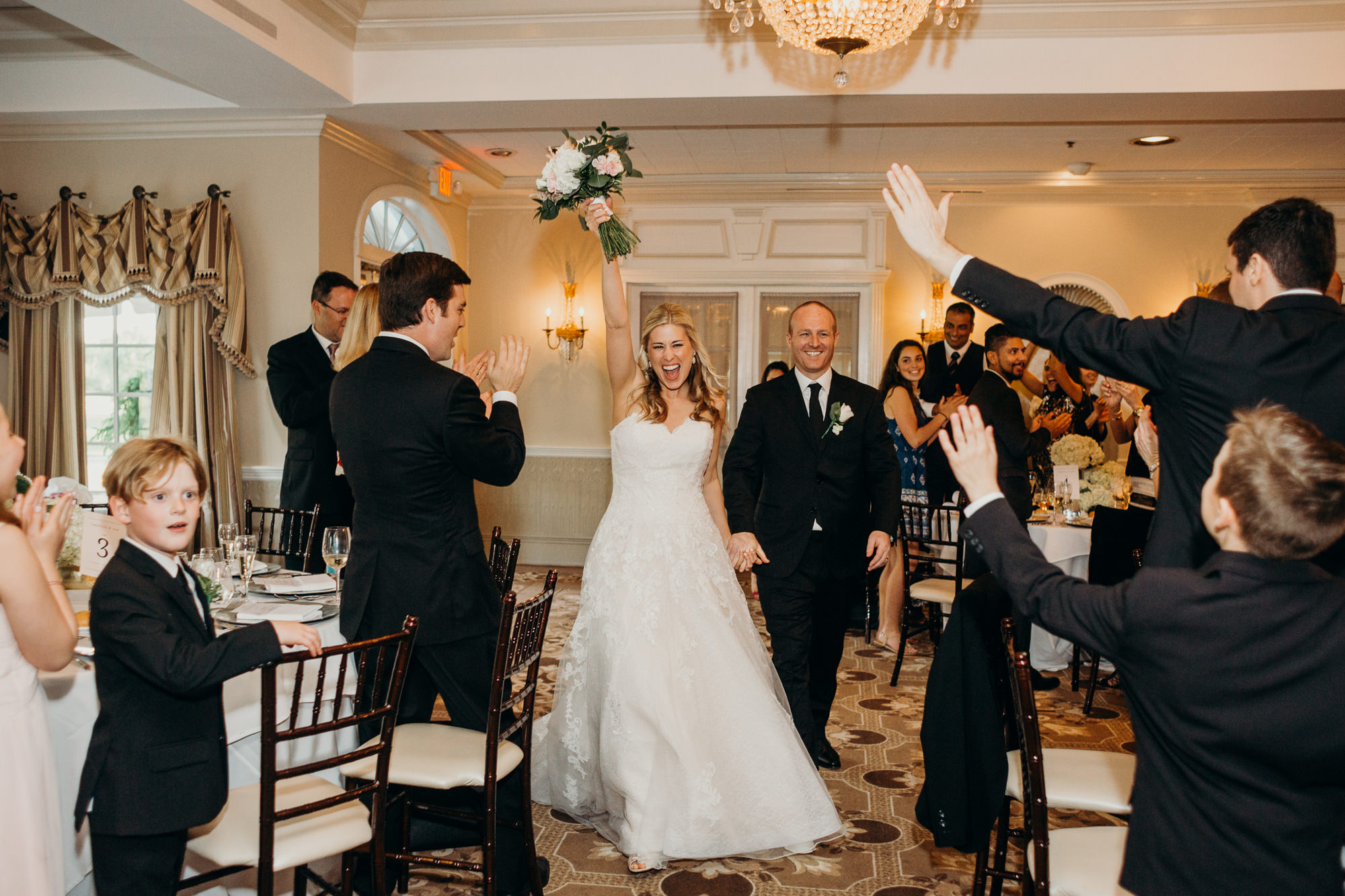 a bride and groom enter their reception at the upper montclair country club in montclair, new jersey