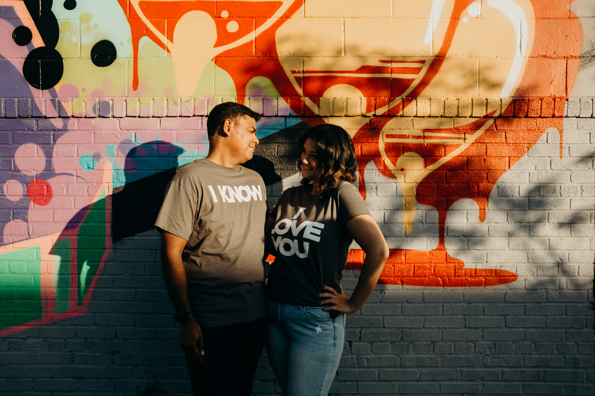 a couple stands in front of a mural in bushwick, brooklyn