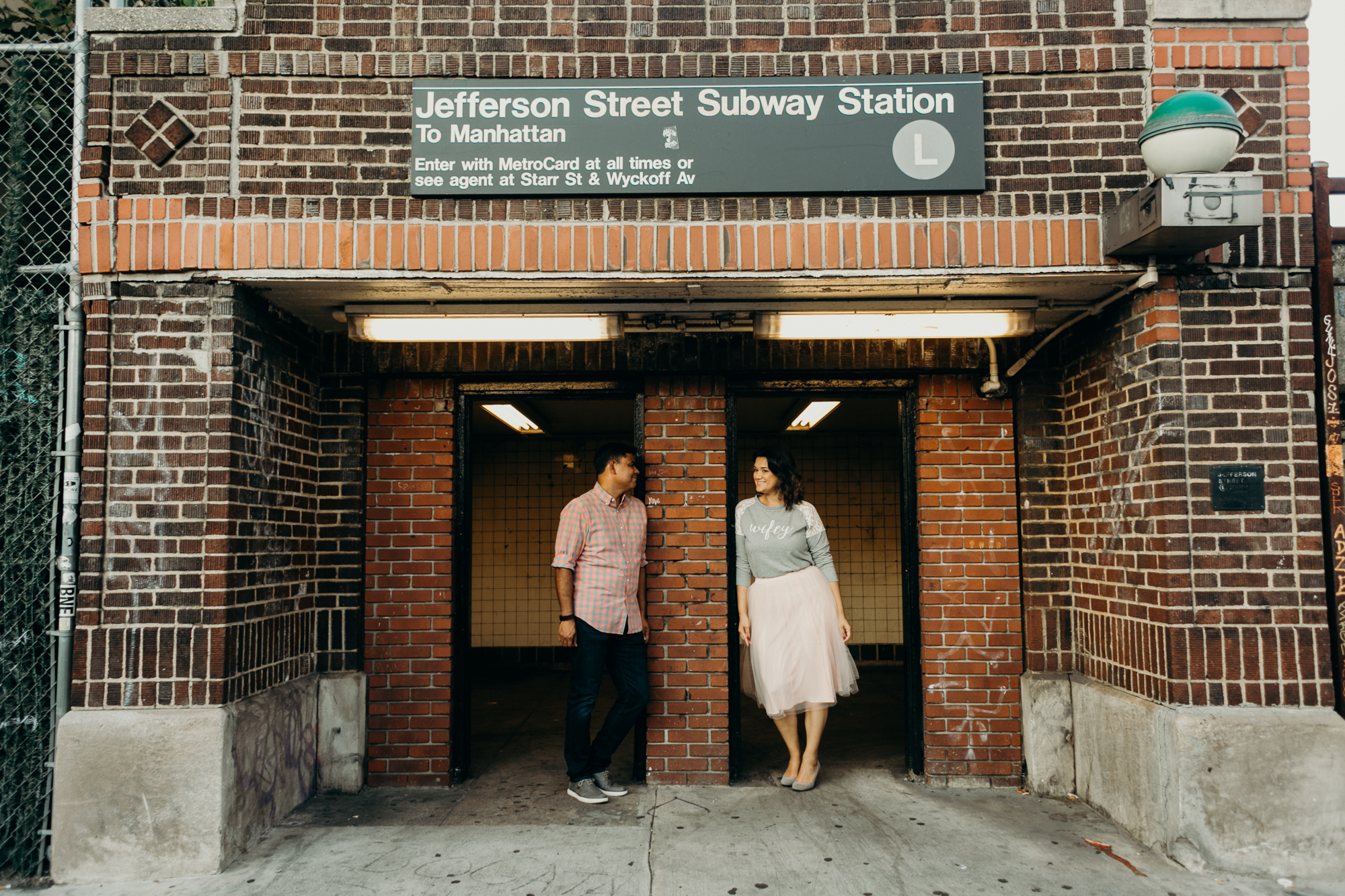 a couple stands in front of a subway station in bushwick, brooklyn