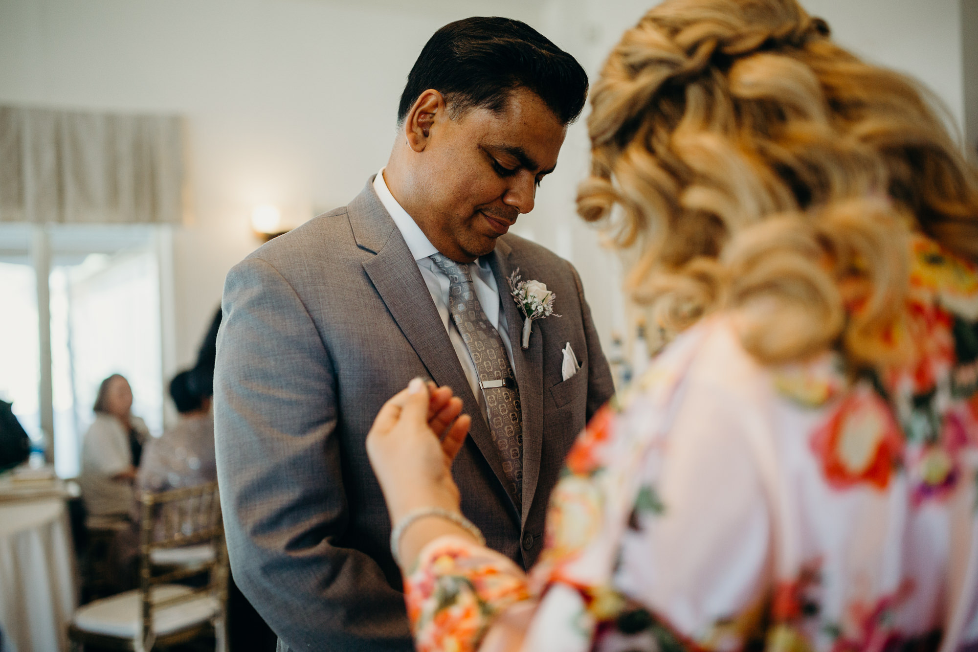 a groom puts on his boutonniere before his wedding at a country club in long island, ny