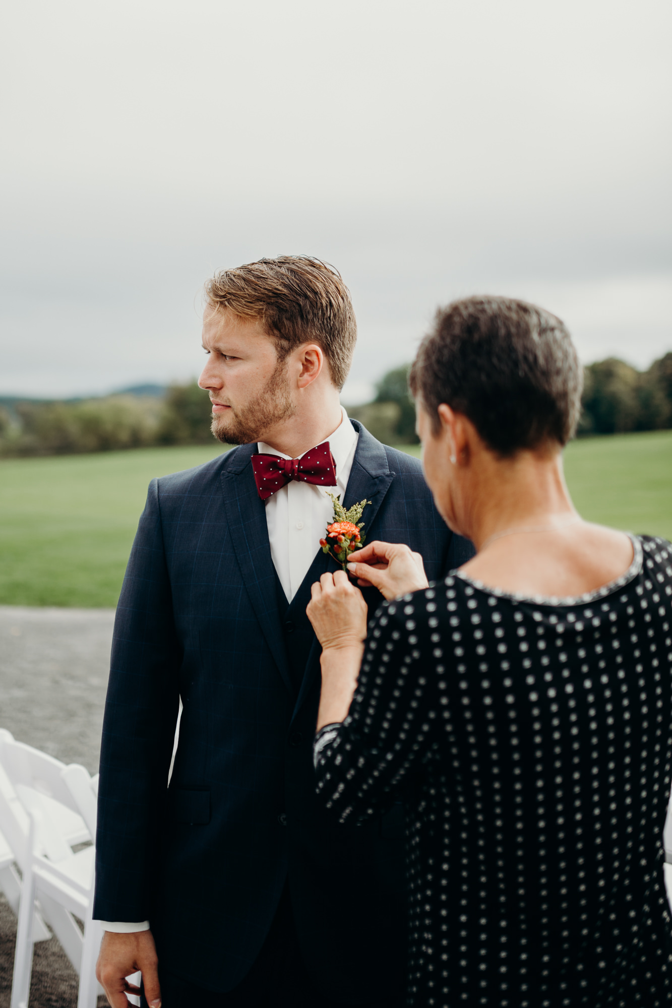 a groom puts on his boutonniere before his wedding at hayloft on the arch in syracuse, ny