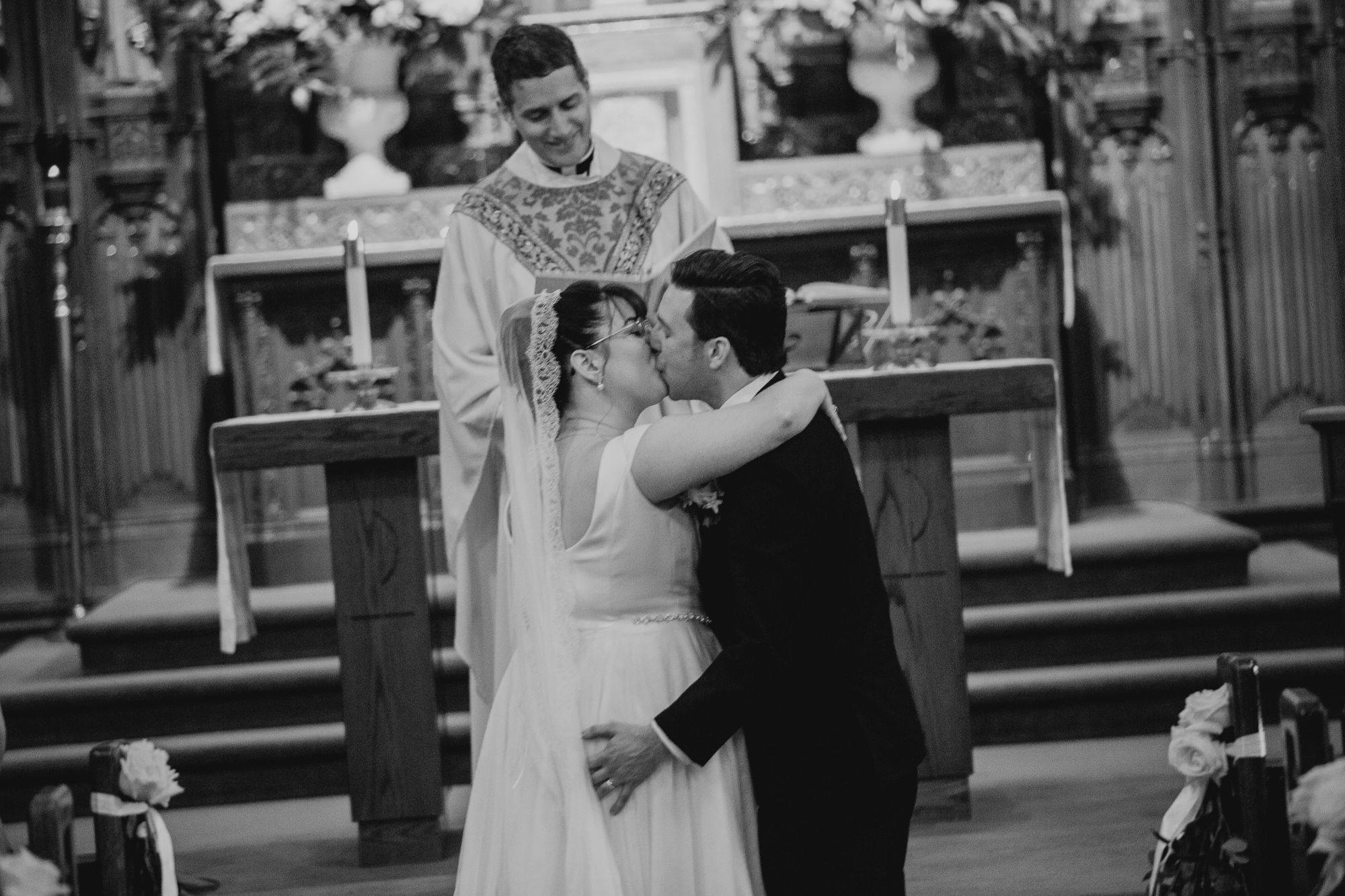 a couple kiss during their wedding ceremony at a church in rochester, ny