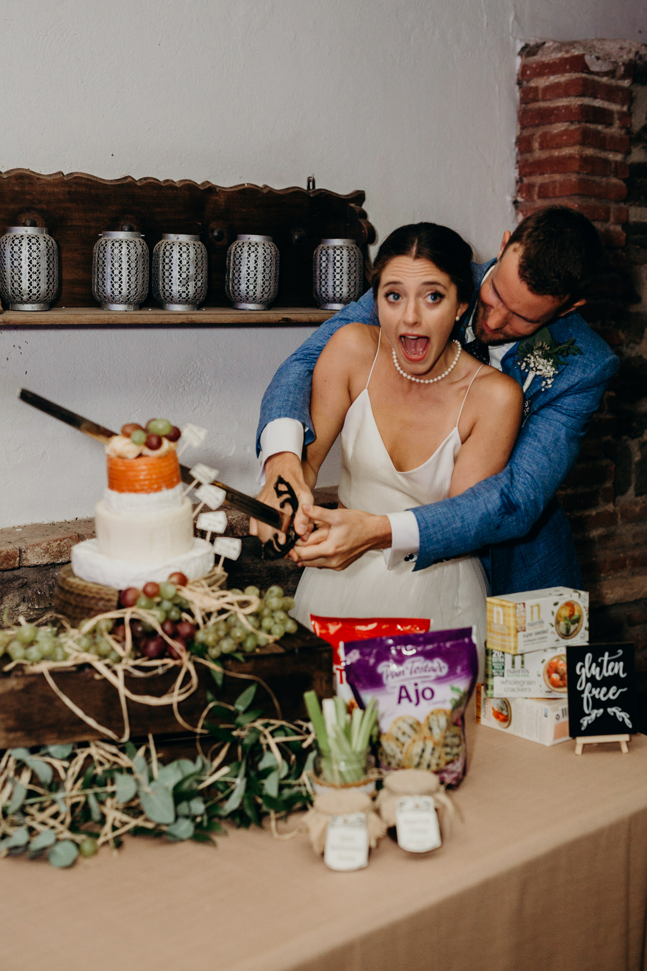 a bride and groom cut their cheese wedding cake at casa de los bates in nerja, spain