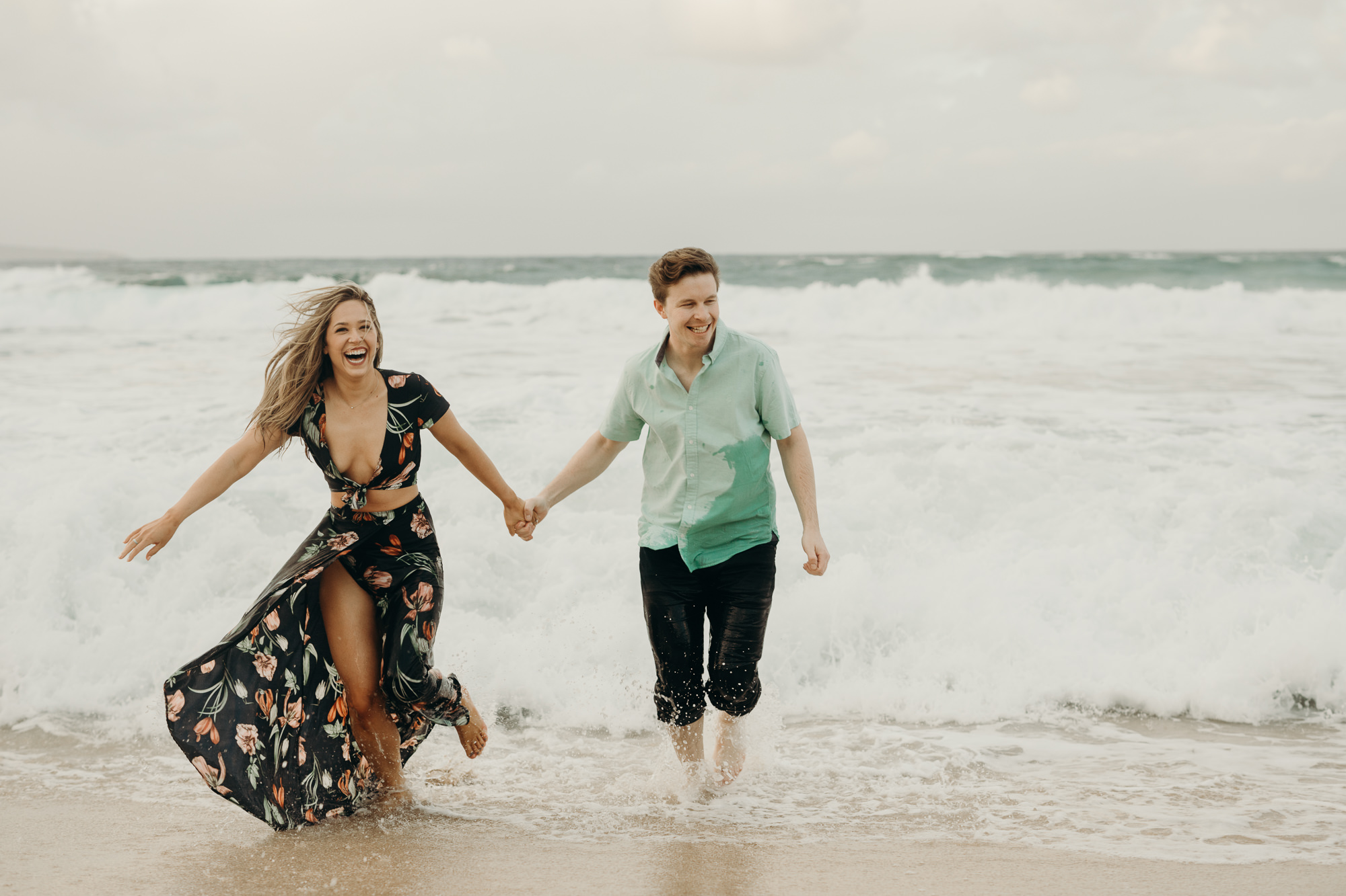 portrait of a couple running in the ocean in maui, HI