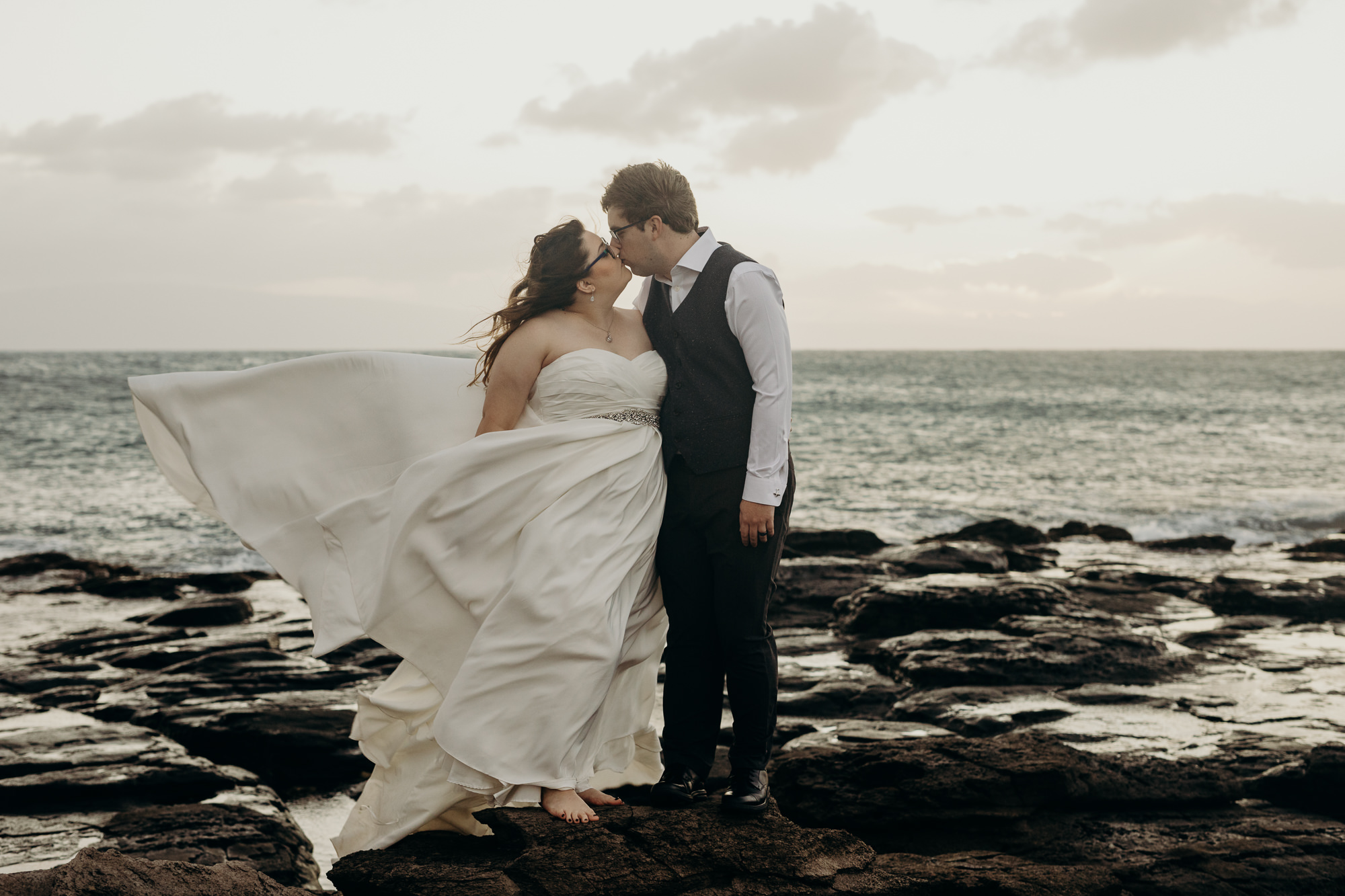 bride and groom portrait on rocks overlooking the ocean at merrimans maui in maui, HI