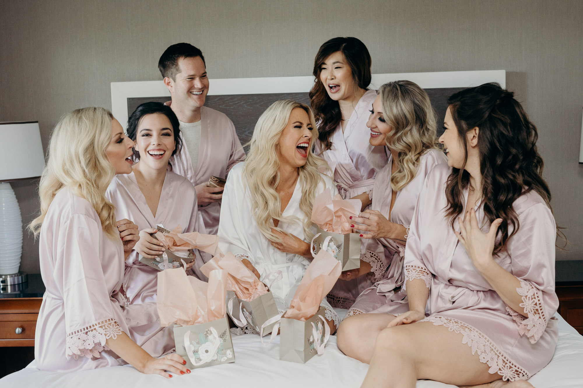 bride and bridesmaids sitting on a bed at five crowns in newport CA