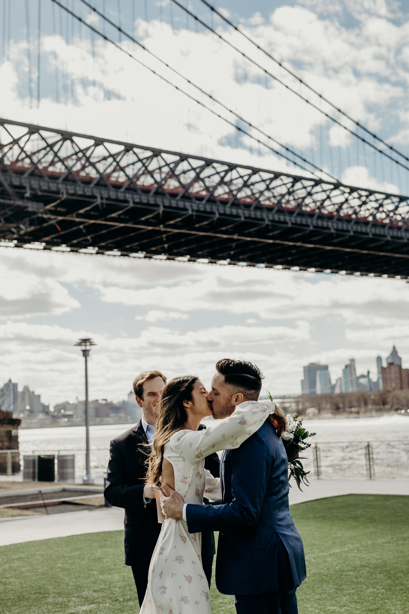 bride and groom kiss during their wedding ceremony at domino park in brooklyn, ny