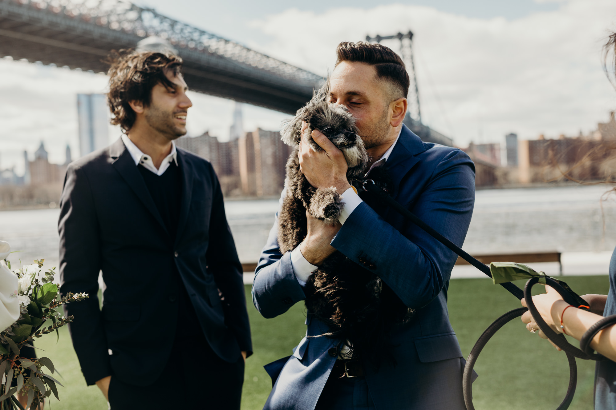 groom kisses his dog after his wedding ceremony at domino park in brooklyn, ny