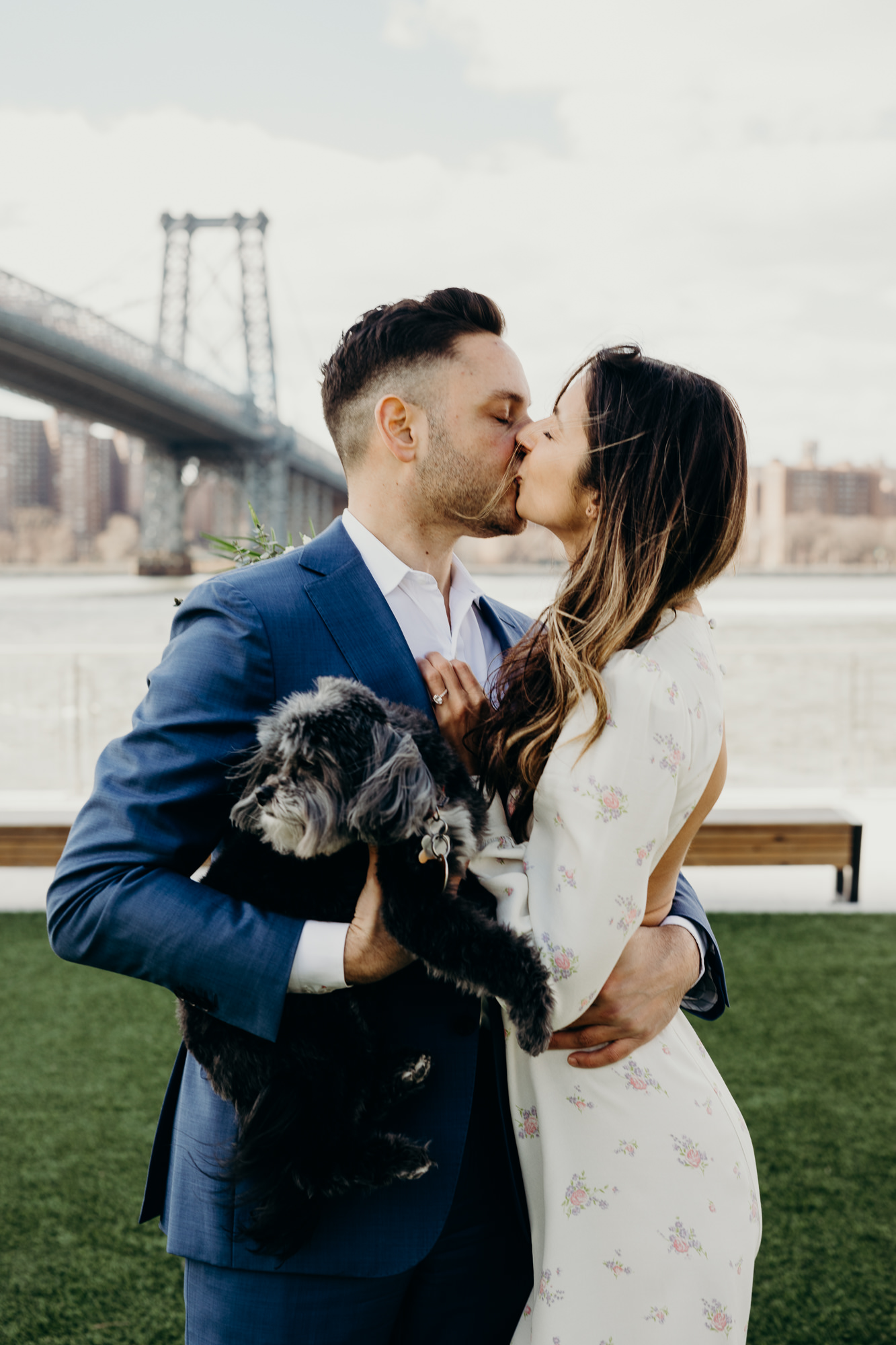 portrait of a bride and groom with their dog on their wedding day at domino park in brooklyn, ny