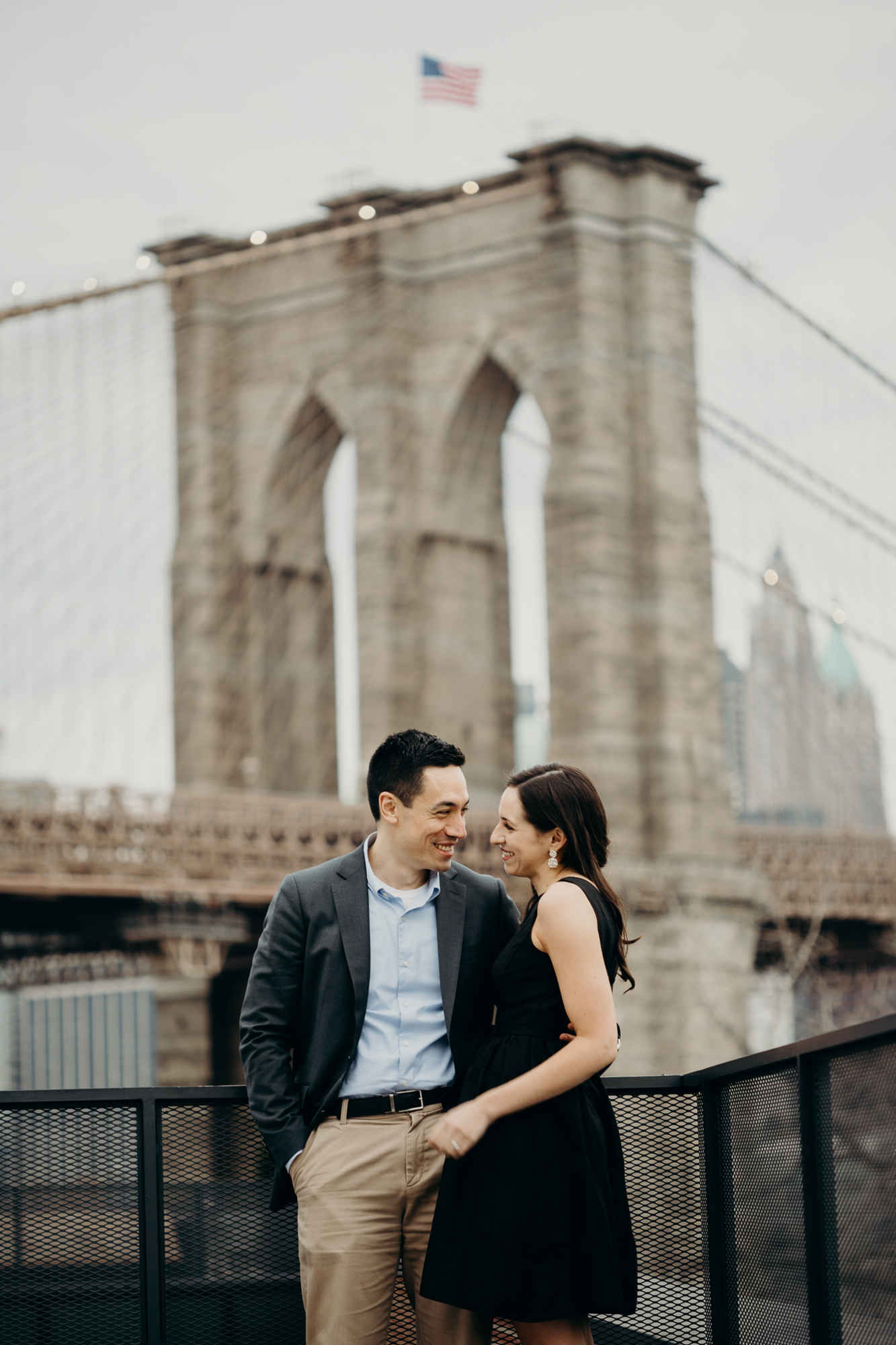 portrait of a couple in front of the brooklyn bridge at brooklyn bridge park in brooklyn, new york