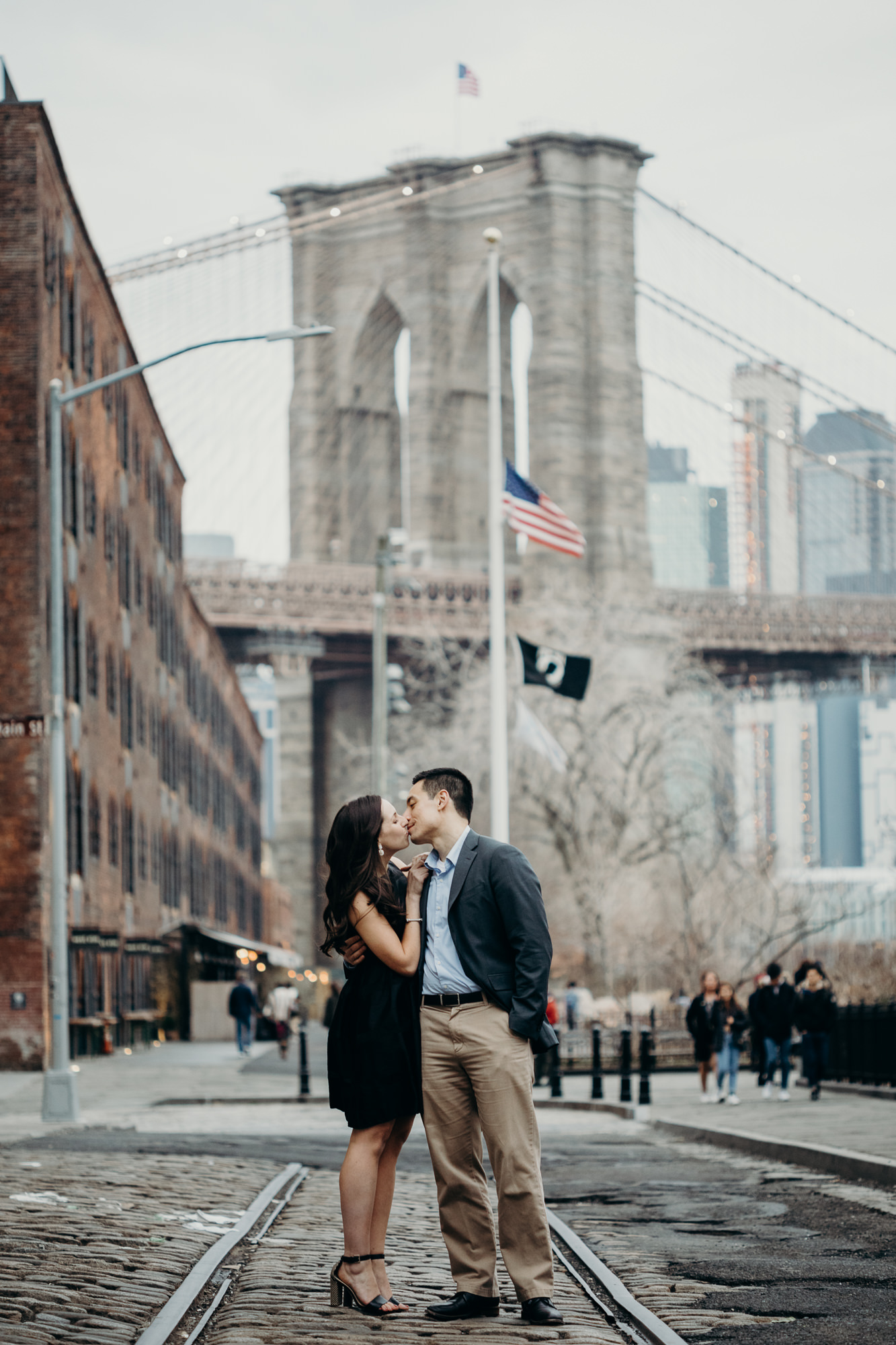 portrait of a couple in front of the brooklyn bridge at brooklyn bridge park in brooklyn, new york