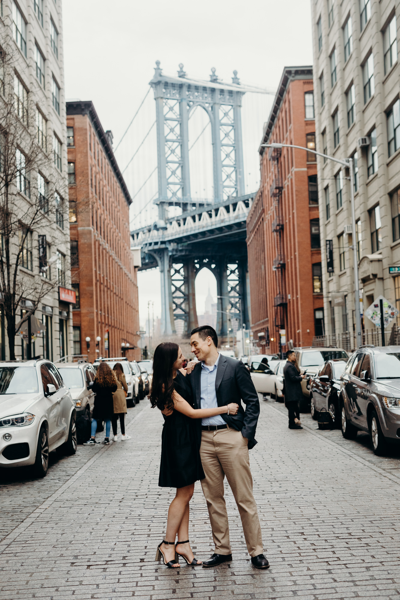 portrait of a couple in front of the manhattan bridge at brooklyn bridge park in brooklyn, new york