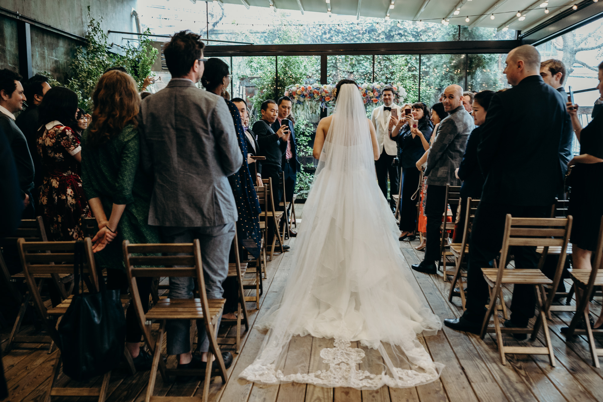 a bride walks down the aisle at her wedding at mymoon in brooklyn, new york