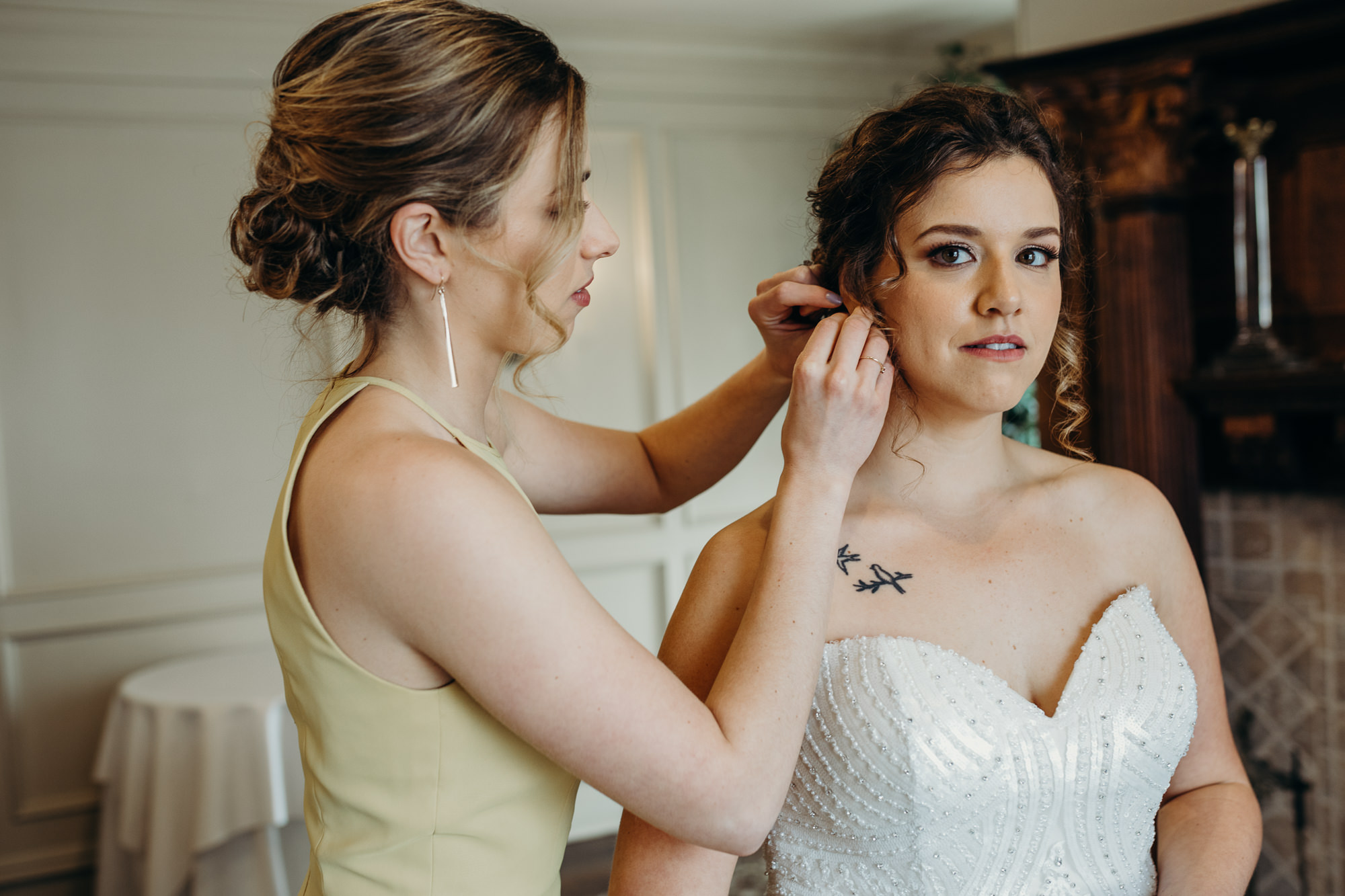 portrait of a bride and her sister putting earrings on at the park savoy in florham park, new jersey