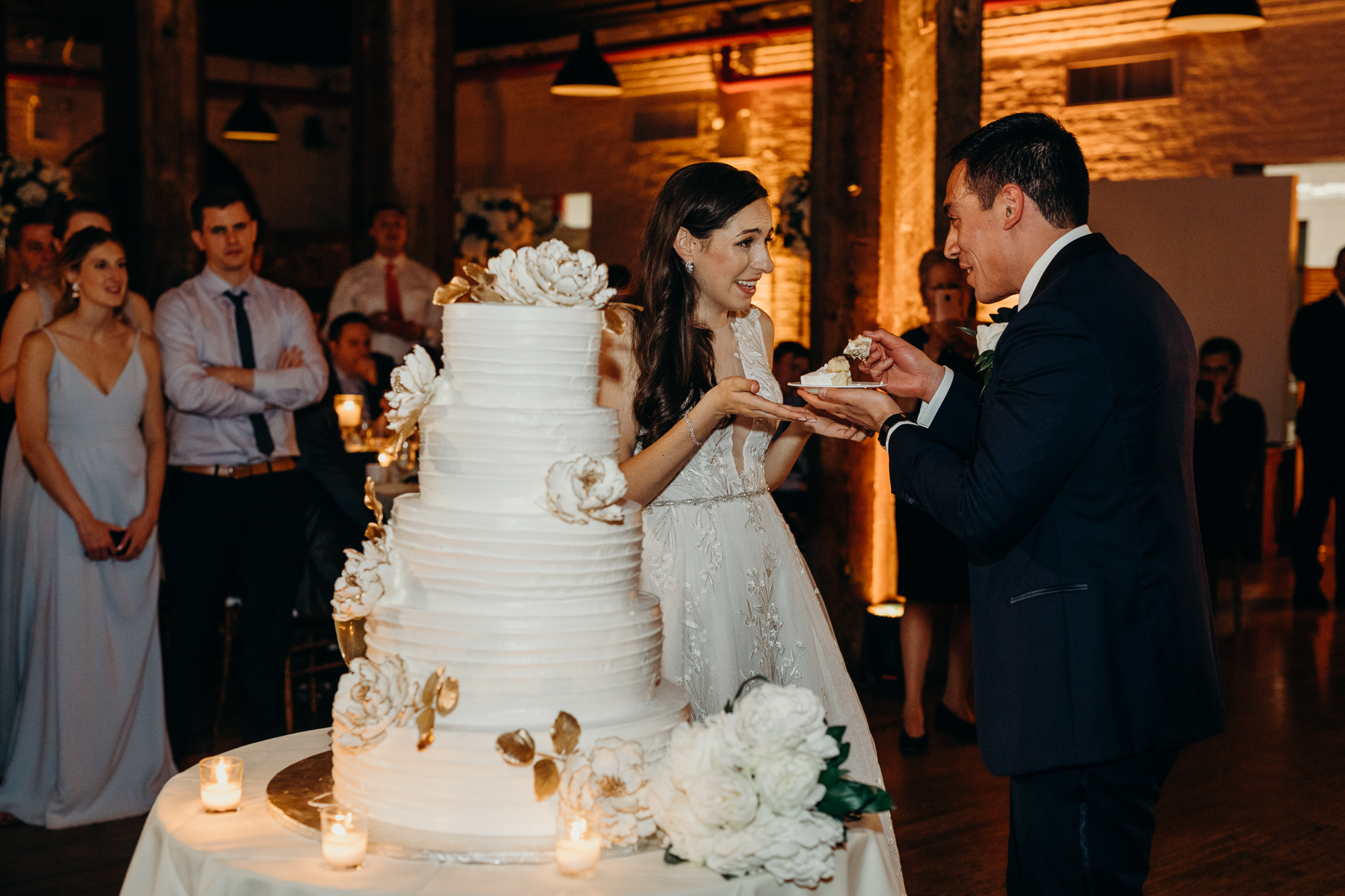 a bride and groom cut their wedding cake at liberty warehouse in brooklyn, new york city