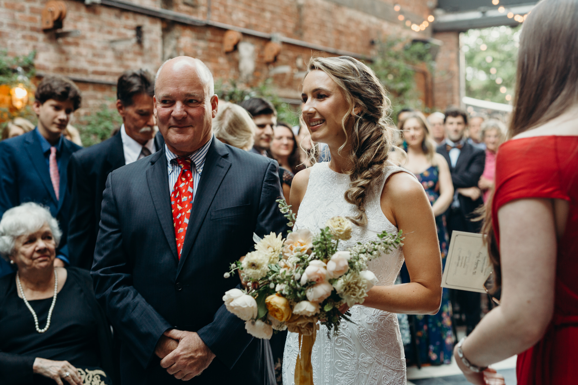 a bride and her father walk down the aisle during a wedding ceremony at the wythe hotel in brooklyn, new york city