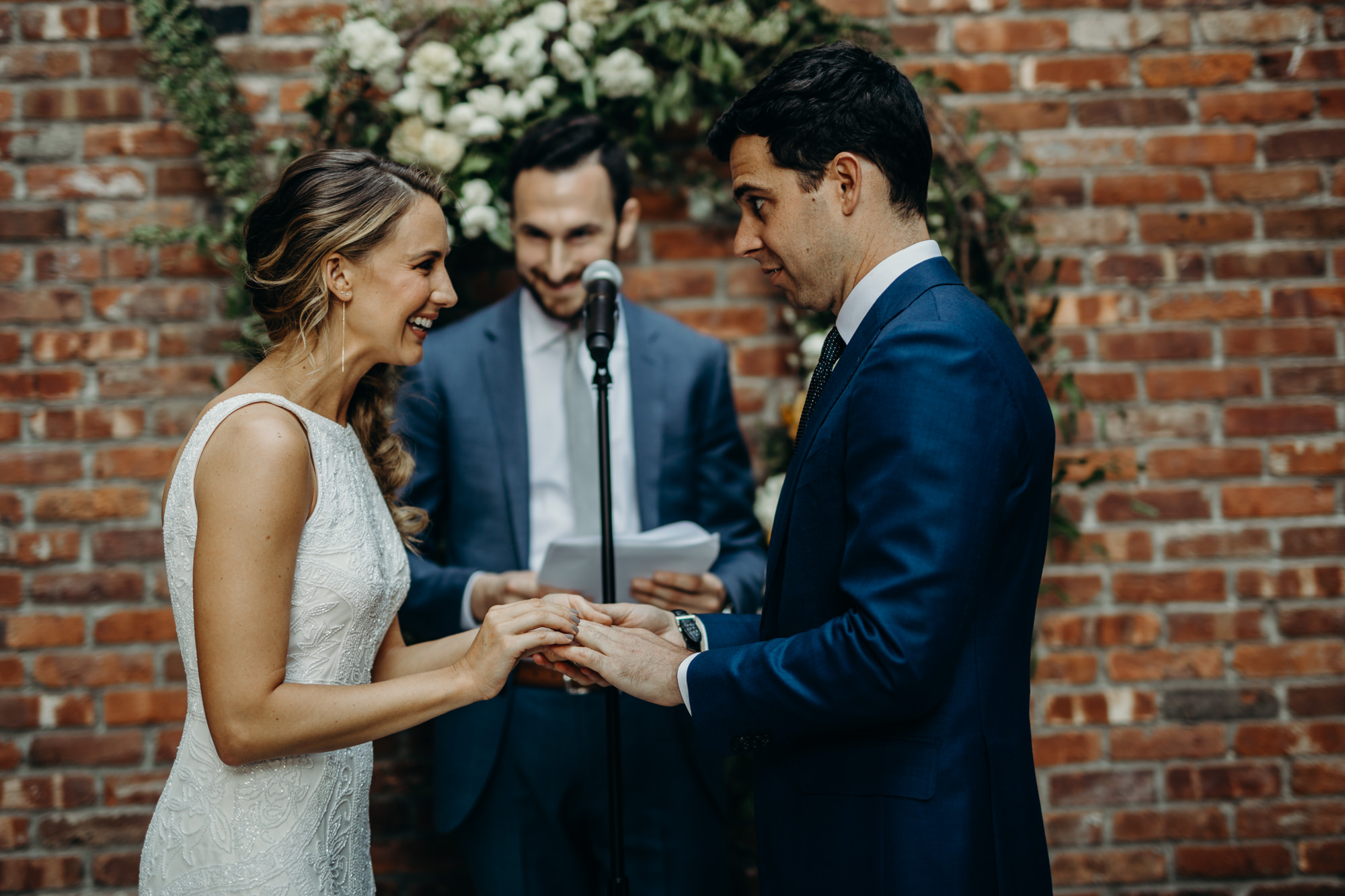 a bride and groom exchange rings at a wedding ceremony at the wythe hotel in brooklyn, new york city