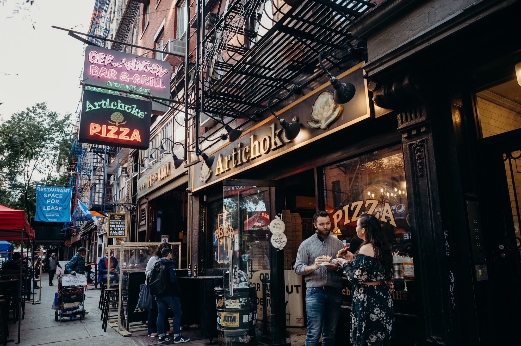 engagement photos of a couple eating pizza at artichoke pizza in the west village, new york city