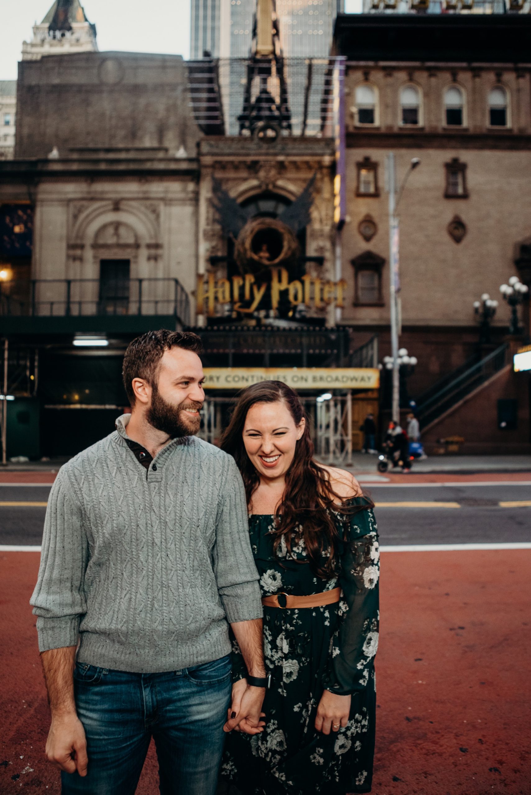 engagement photos of a couple in front of the lyric theater in times square, new york city