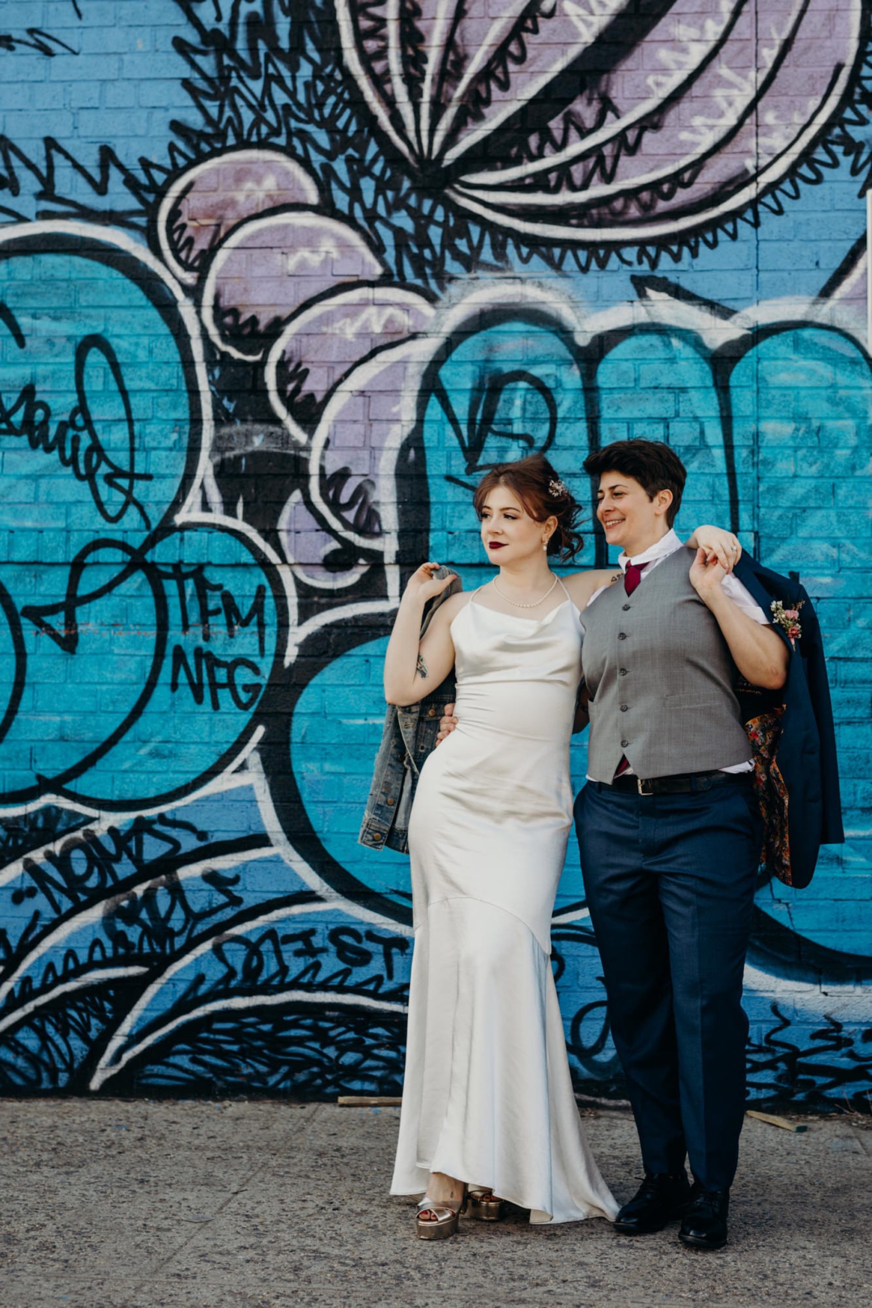 portrait of a couple just married in front of streetart in bushwick, brooklyn, new york city