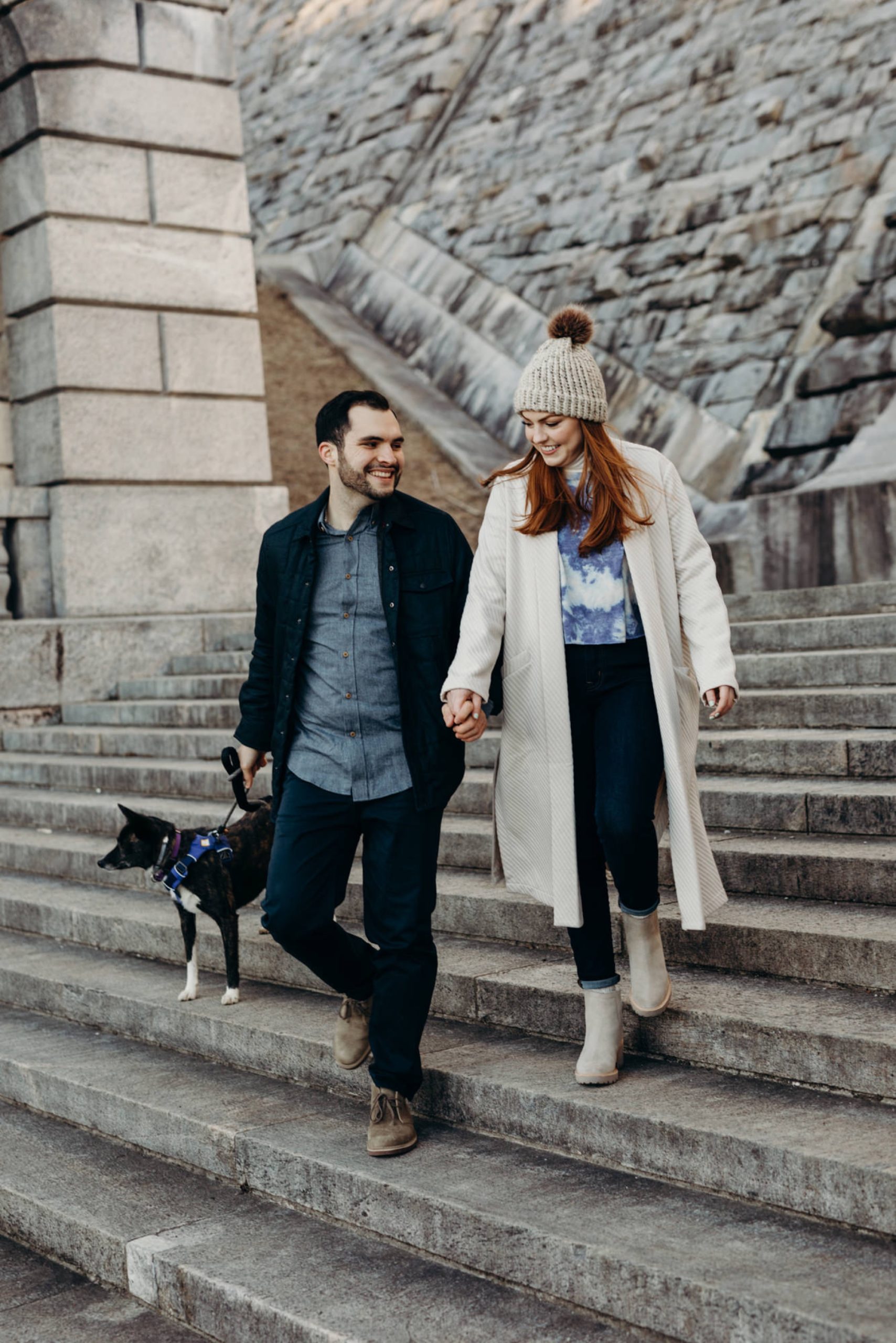 a engagement portrait of a couple walking with their dog at the kensico dam in white plains, new york