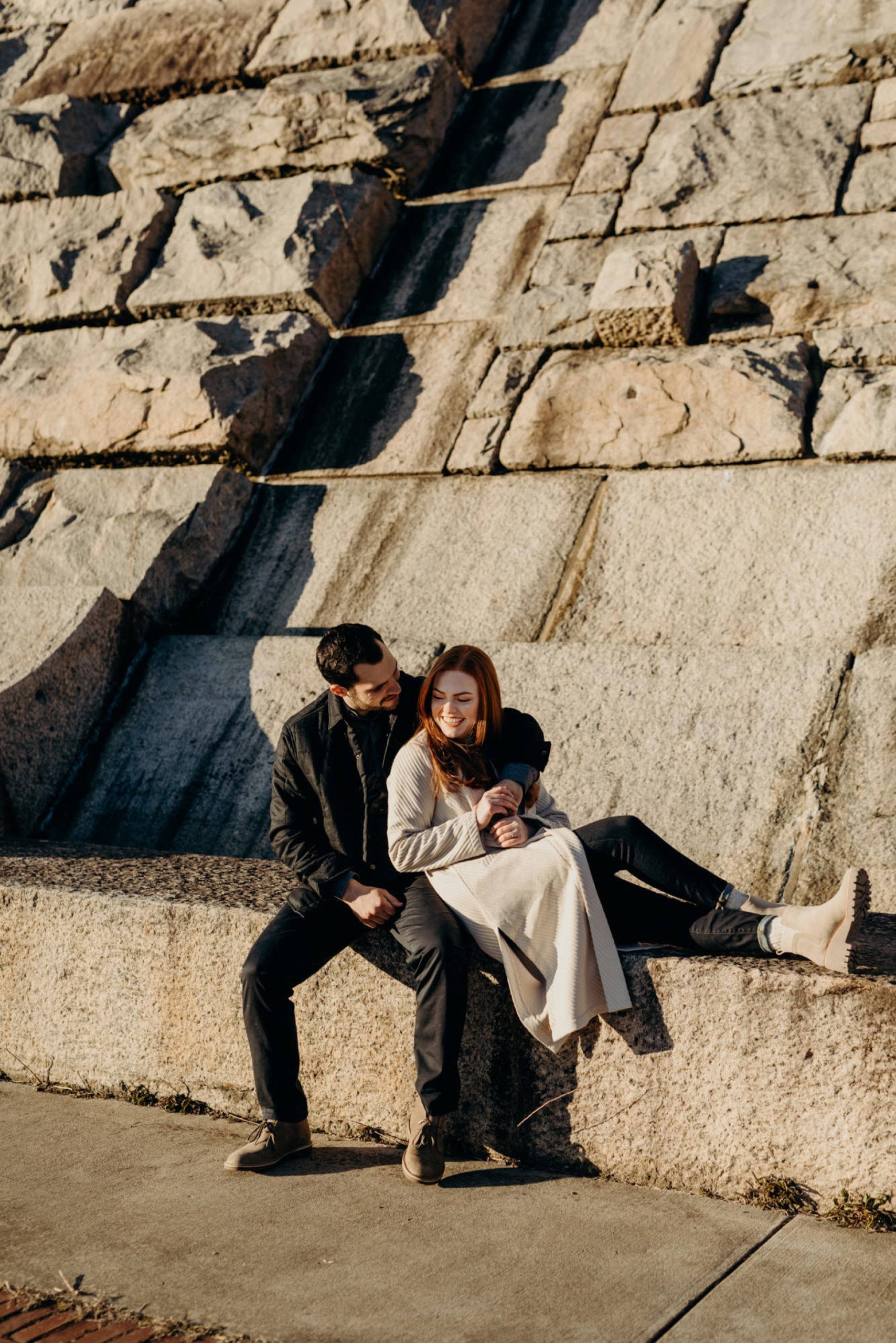a engagement portrait of a couple sitting together at the kensico dam in white plains, new york