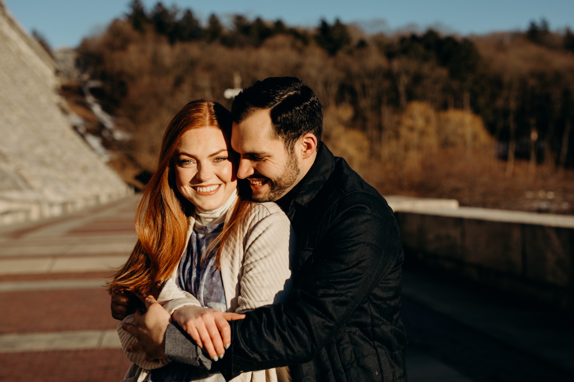 a engagement portrait of a couple hugging at the kensico dam in white plains, new york