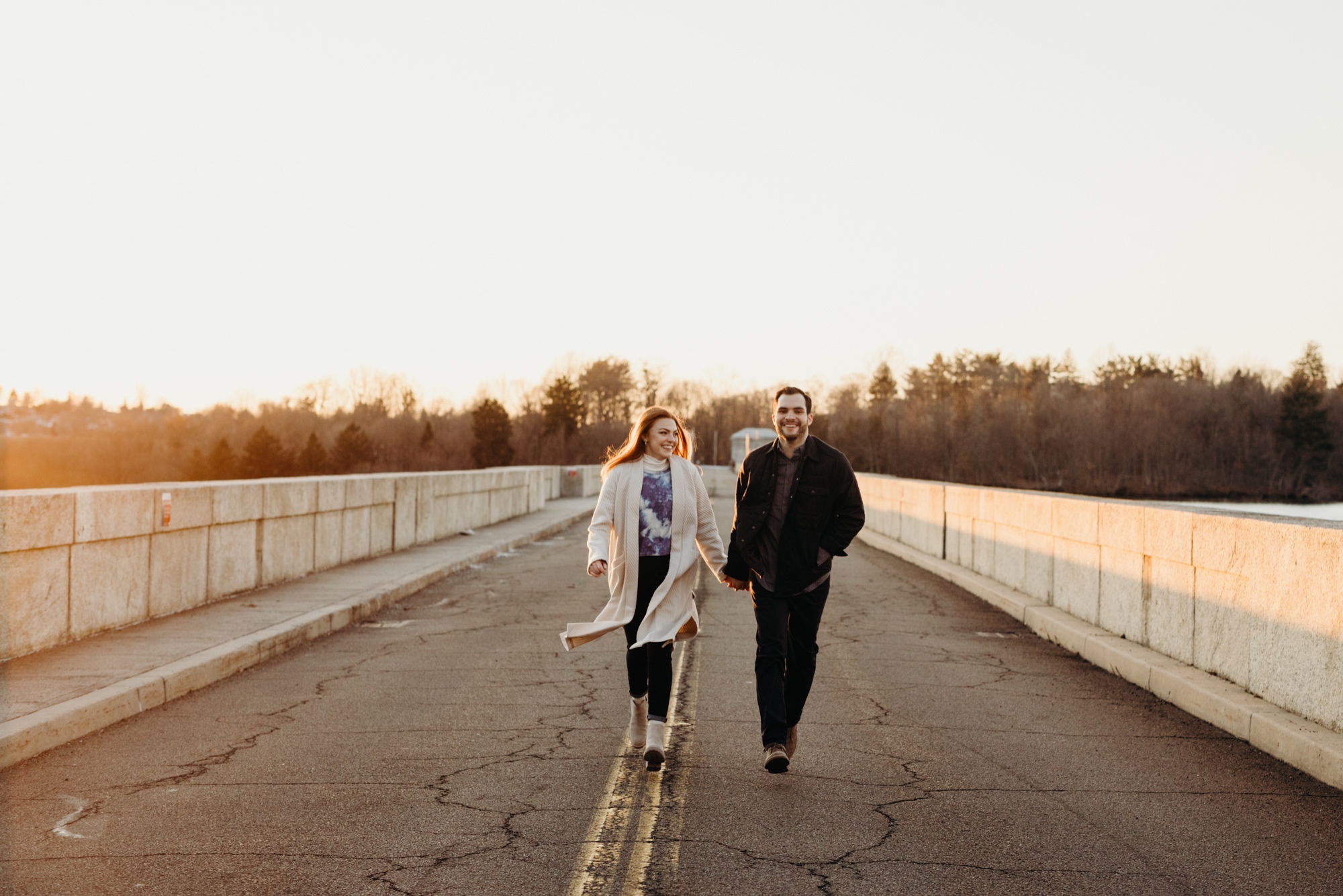 a engagement portrait of a couple running at the kensico dam in white plains, new york