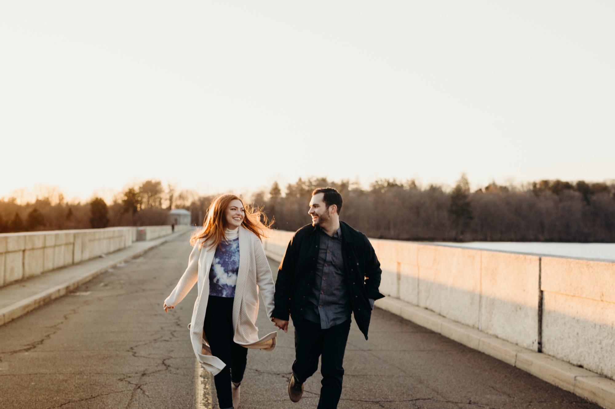 a engagement portrait of a couple running at the kensico dam in white plains, new york