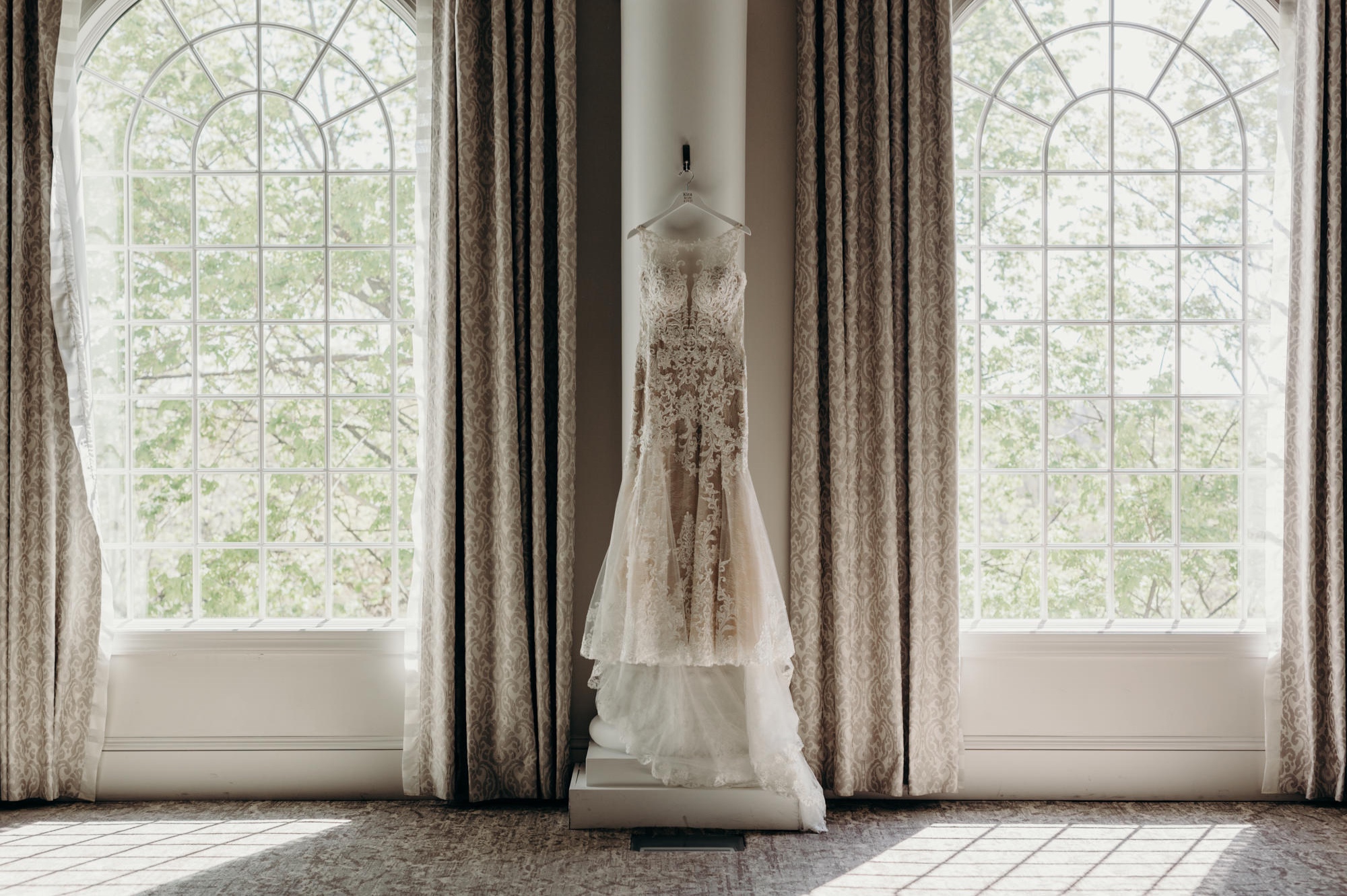 photo of a wedding gown hanging between two windows at valley regency in new jersey