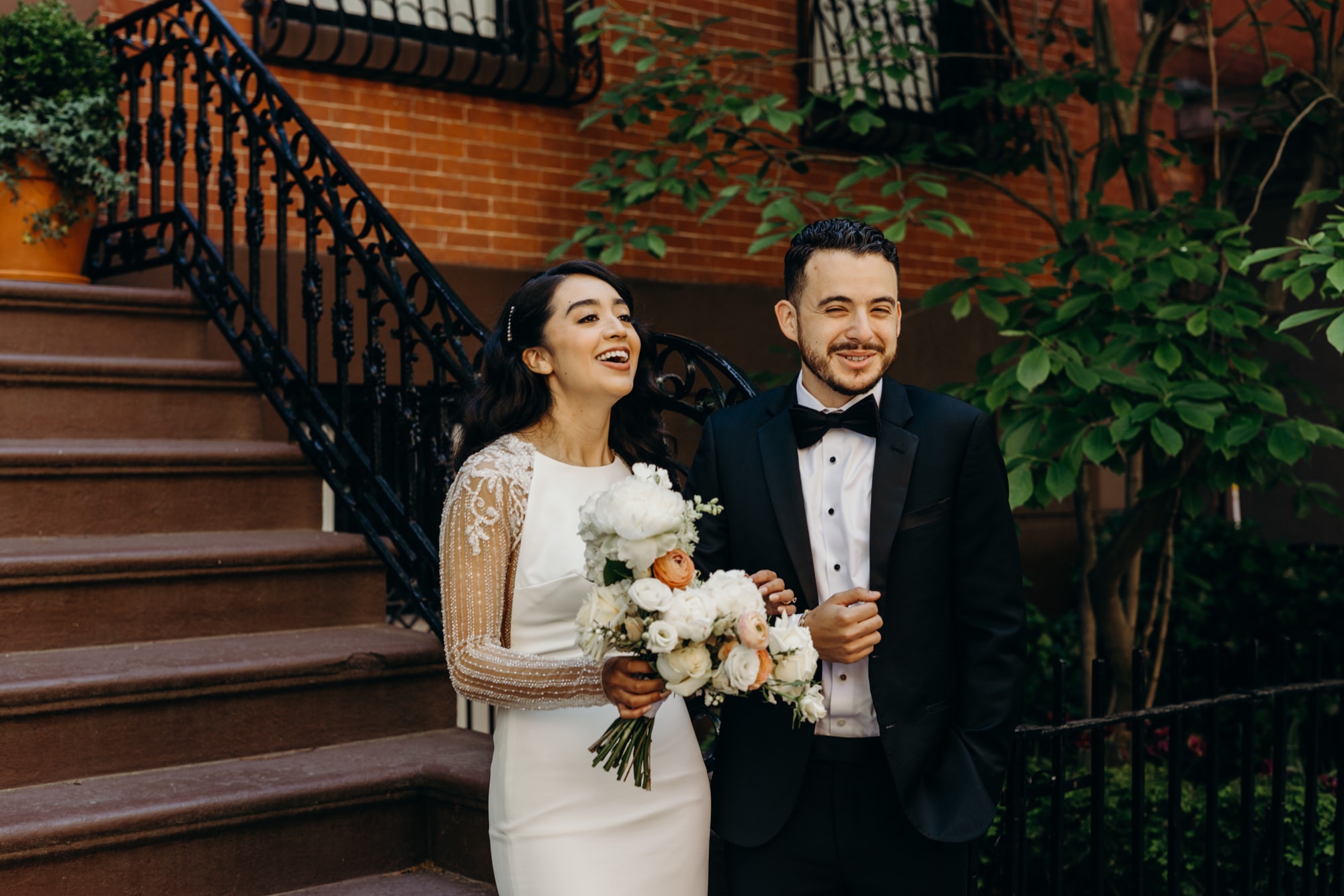 portrait of a bride and groom laughing in front of a brownstone in brooklyn, new york