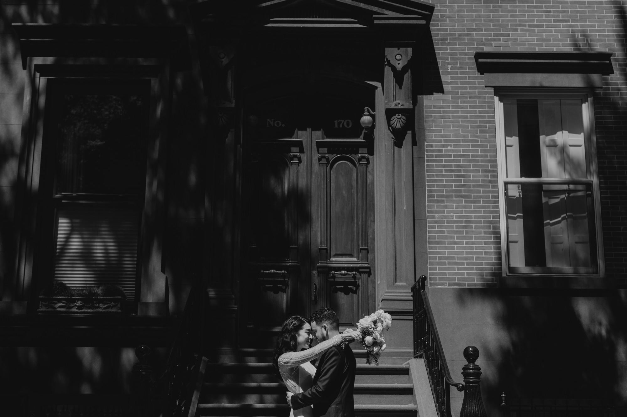 portrait of a bride and groom touching foreheads in front of a brownstone in brooklyn, new york