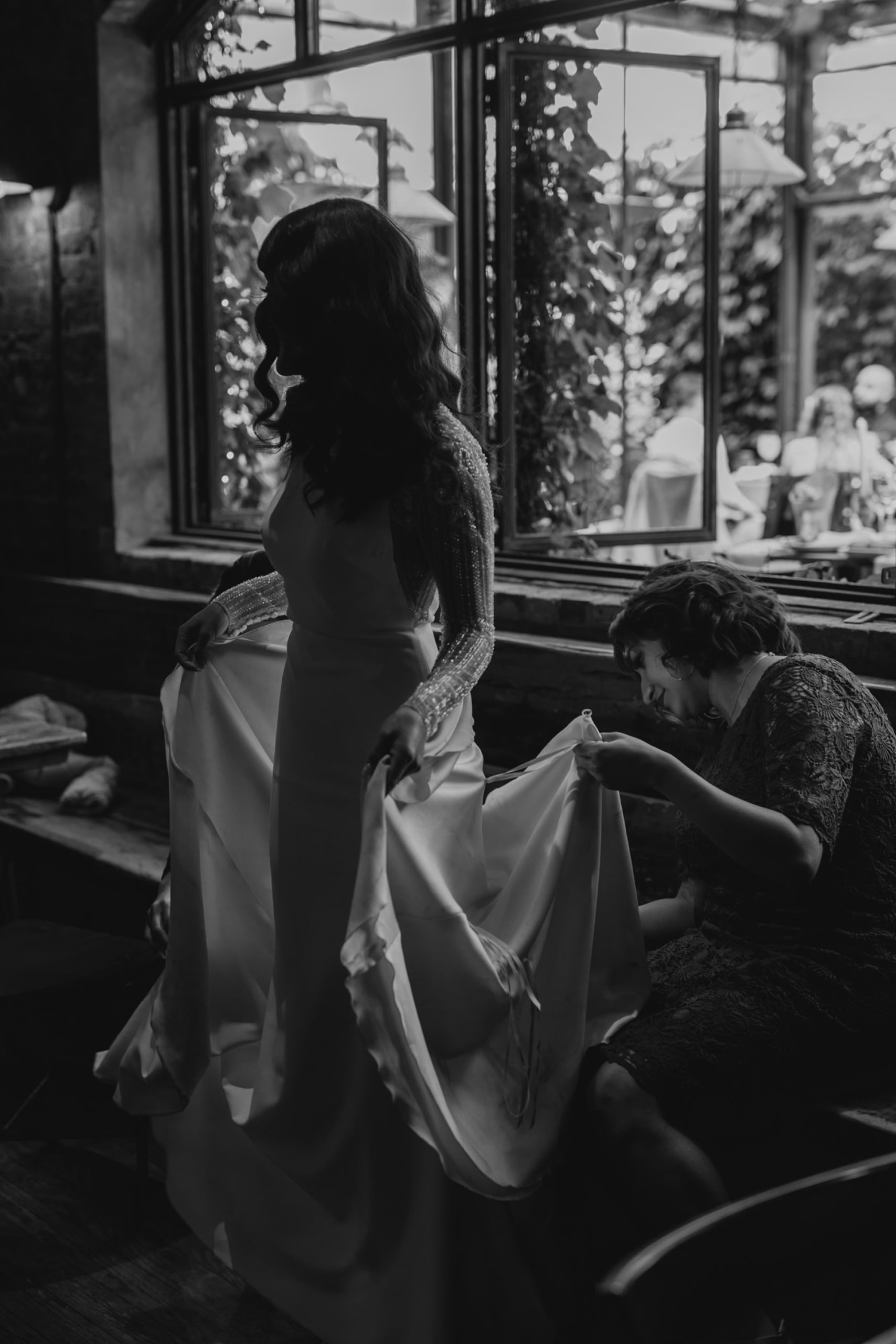 black and white image of a bride having her dress bustled at aurora brooklyn in new york city