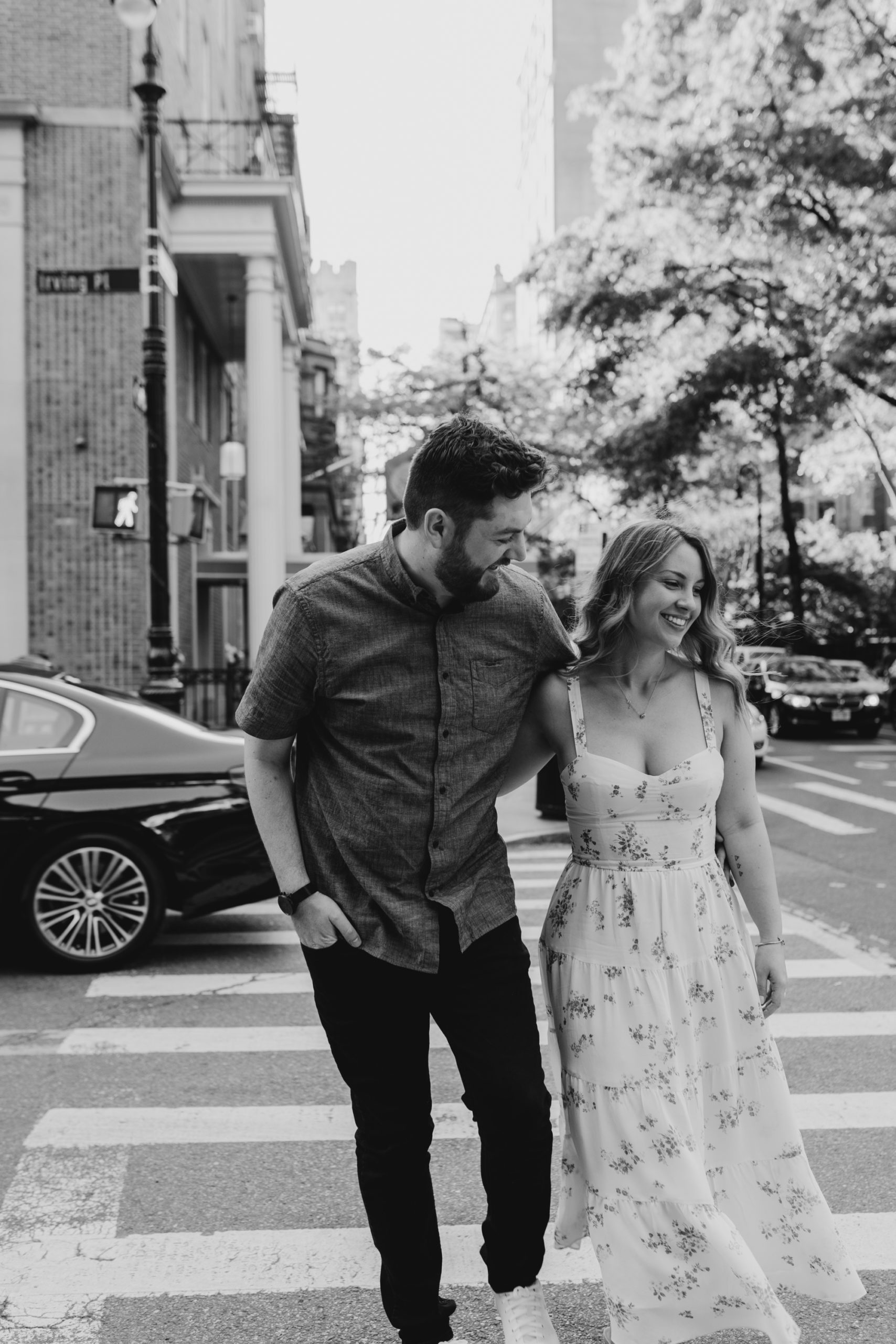 portrait of a couple walking across the street during their engagement session at gramercy park in new york city