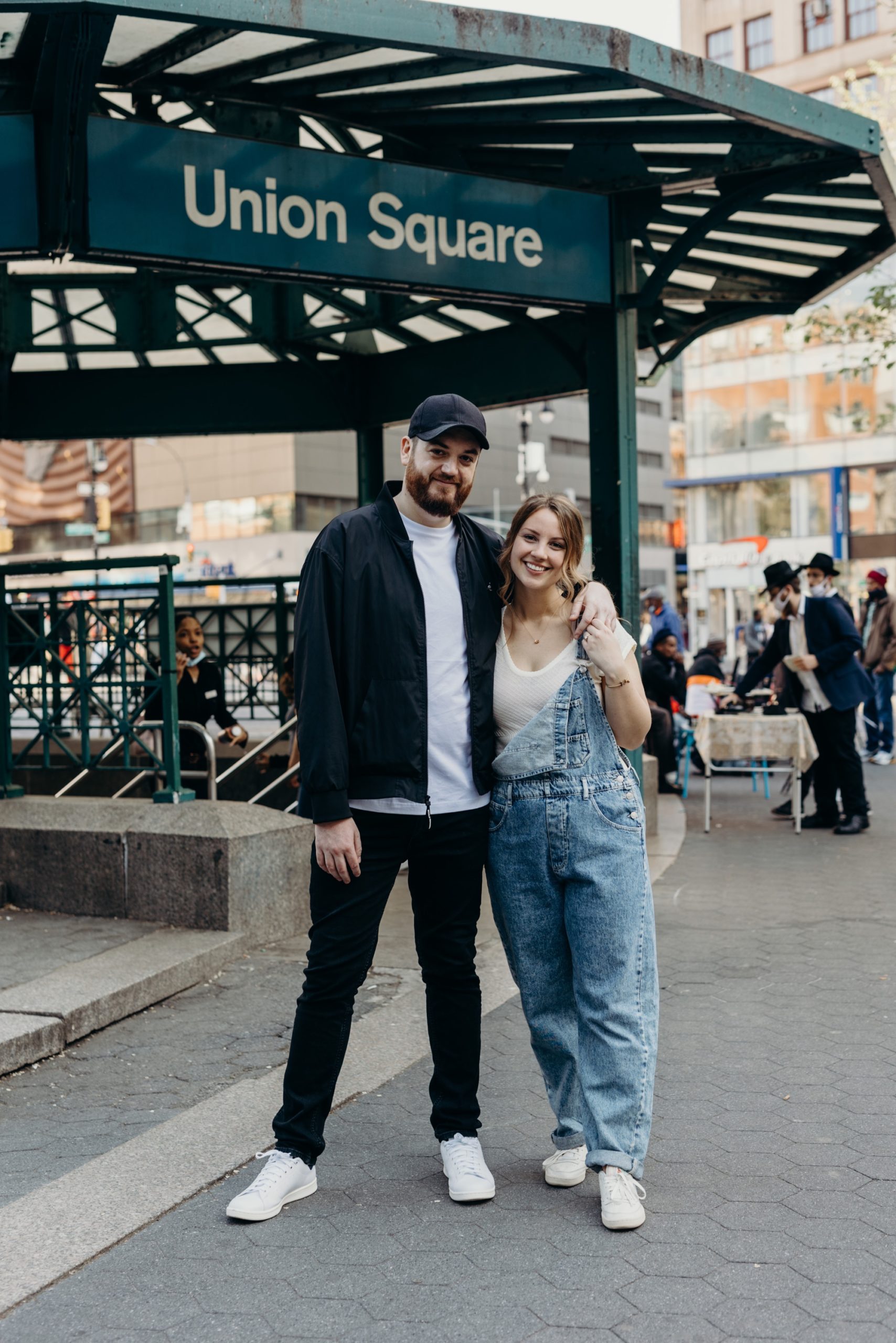 portrait of a couple standing outside of the union square train station durign their nyc engagement session