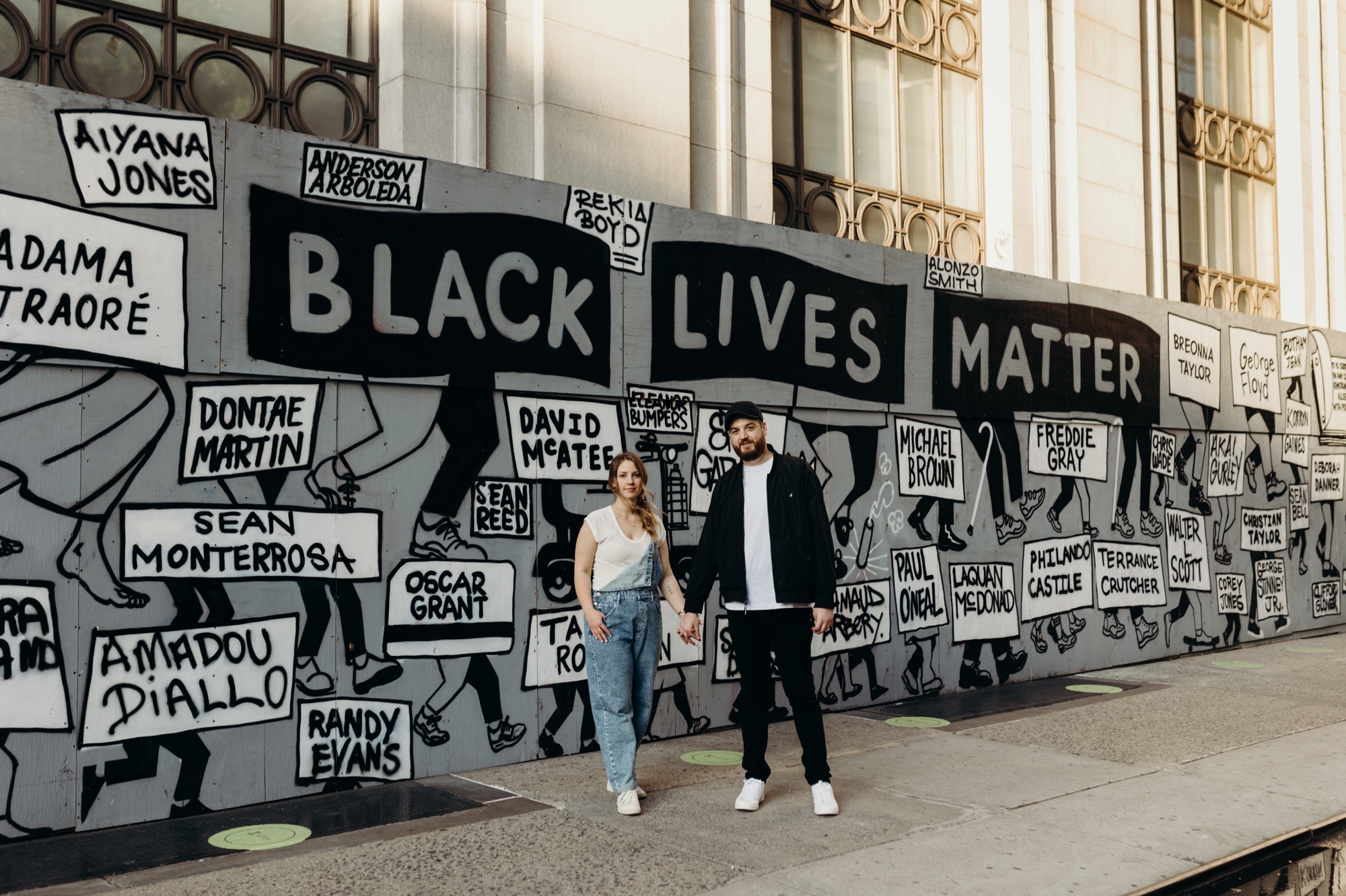 portrait of a couple standing in front of a black lives matter mural in union square during their engagement session in new york city