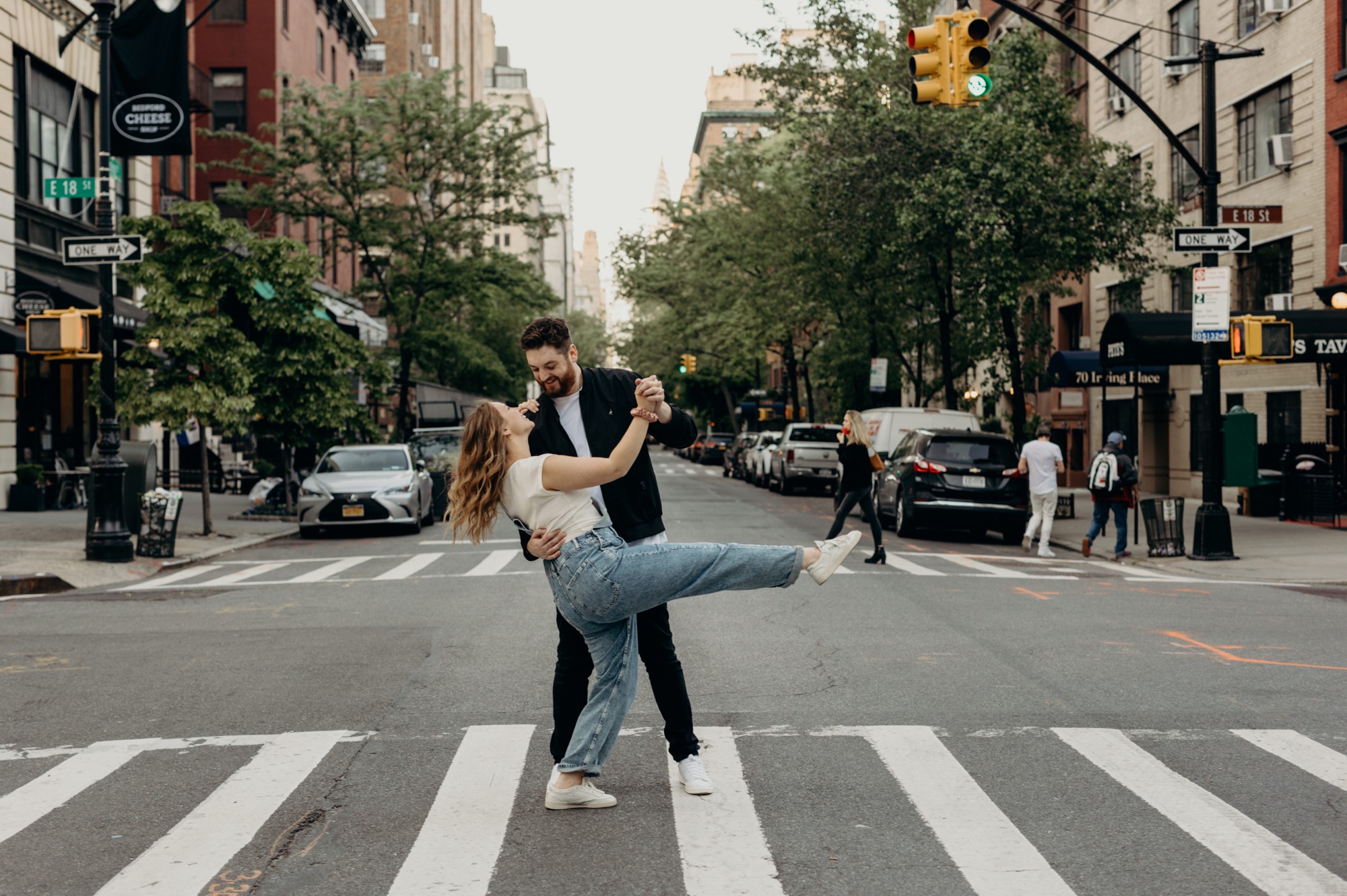 portrait of a couple walking across the street during their engagement session at gramercy park in new york city