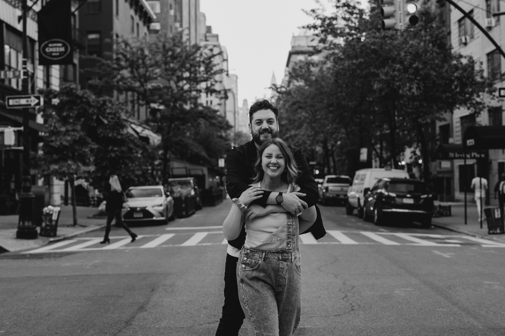 portrait of a couple walking across the street during their engagement session at gramercy park in new york city