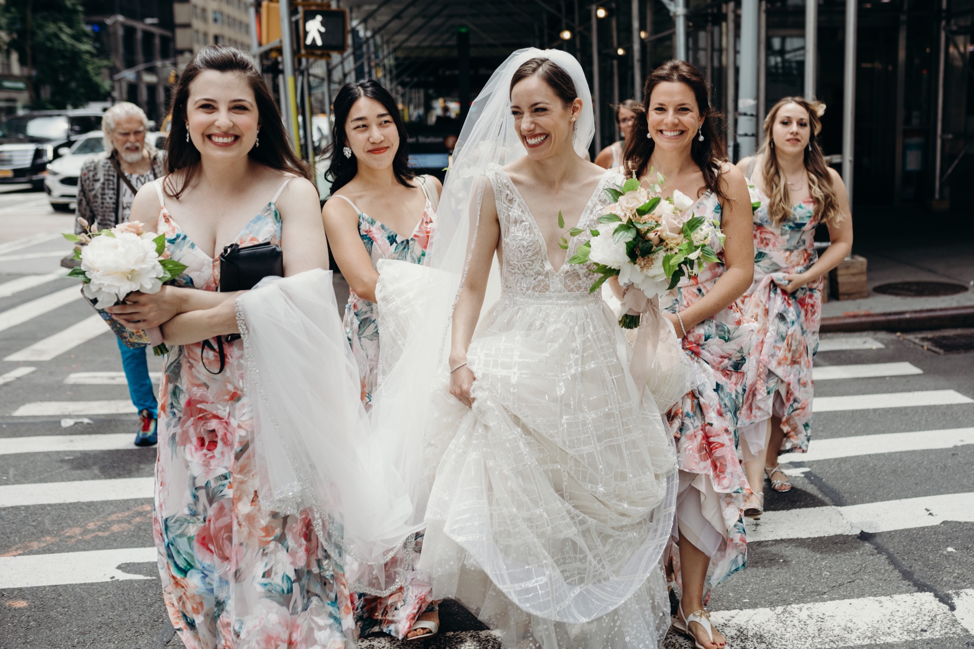 bride walking across a crosswalk with her bridesmaids in new york city