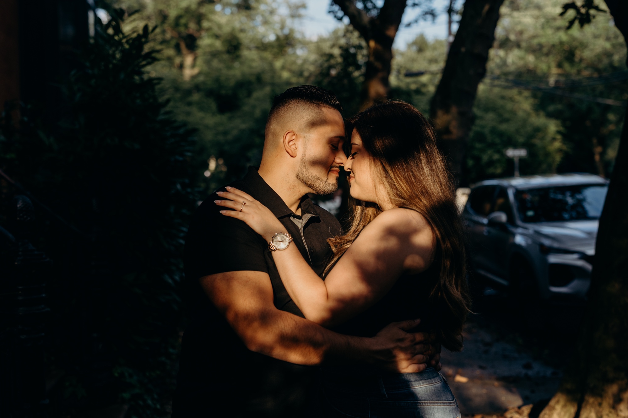 portrait of a couple looking at each other in dappled light on a sidewalk