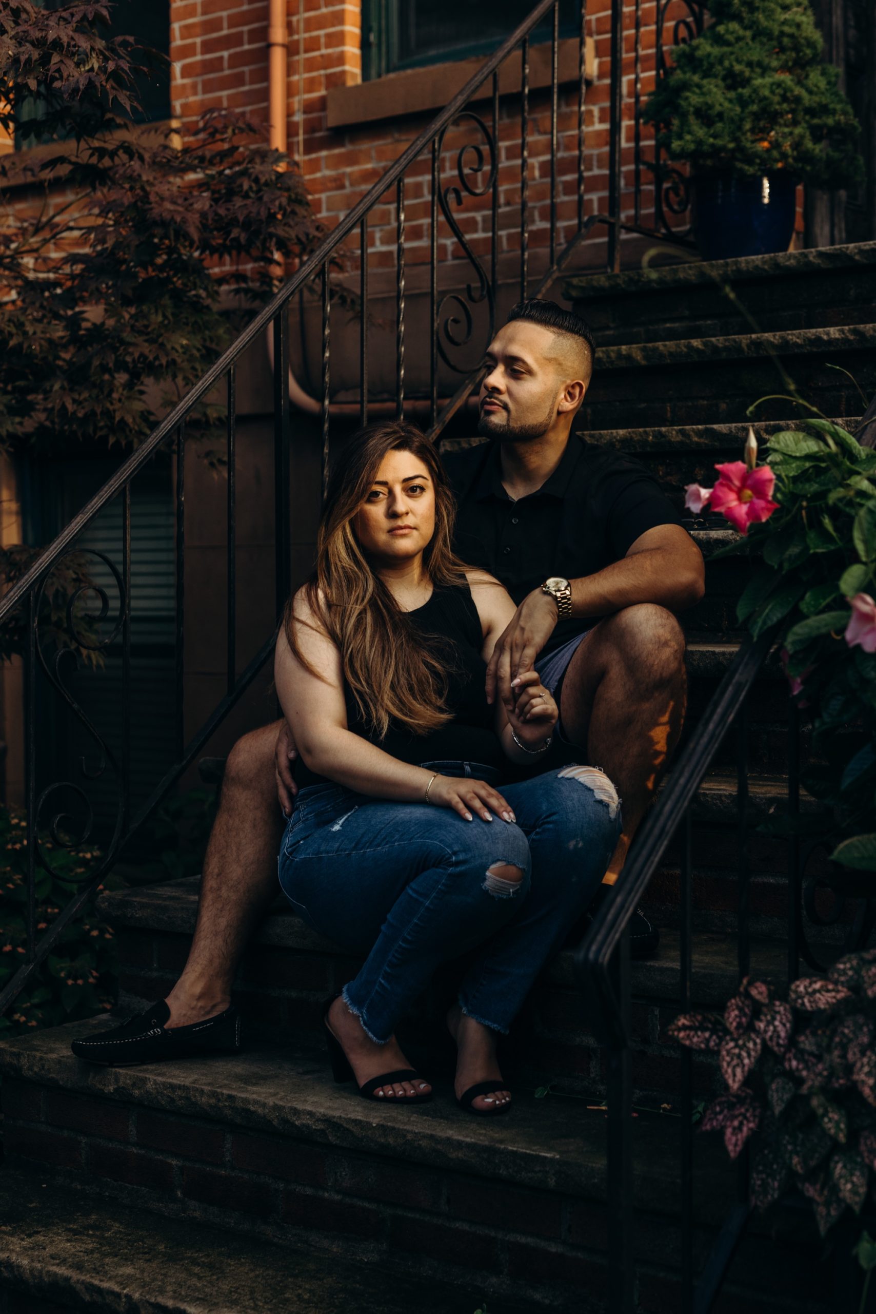 image of a couple sitting on a brownstone stoop, bride is looking at the camera and groom is looking away