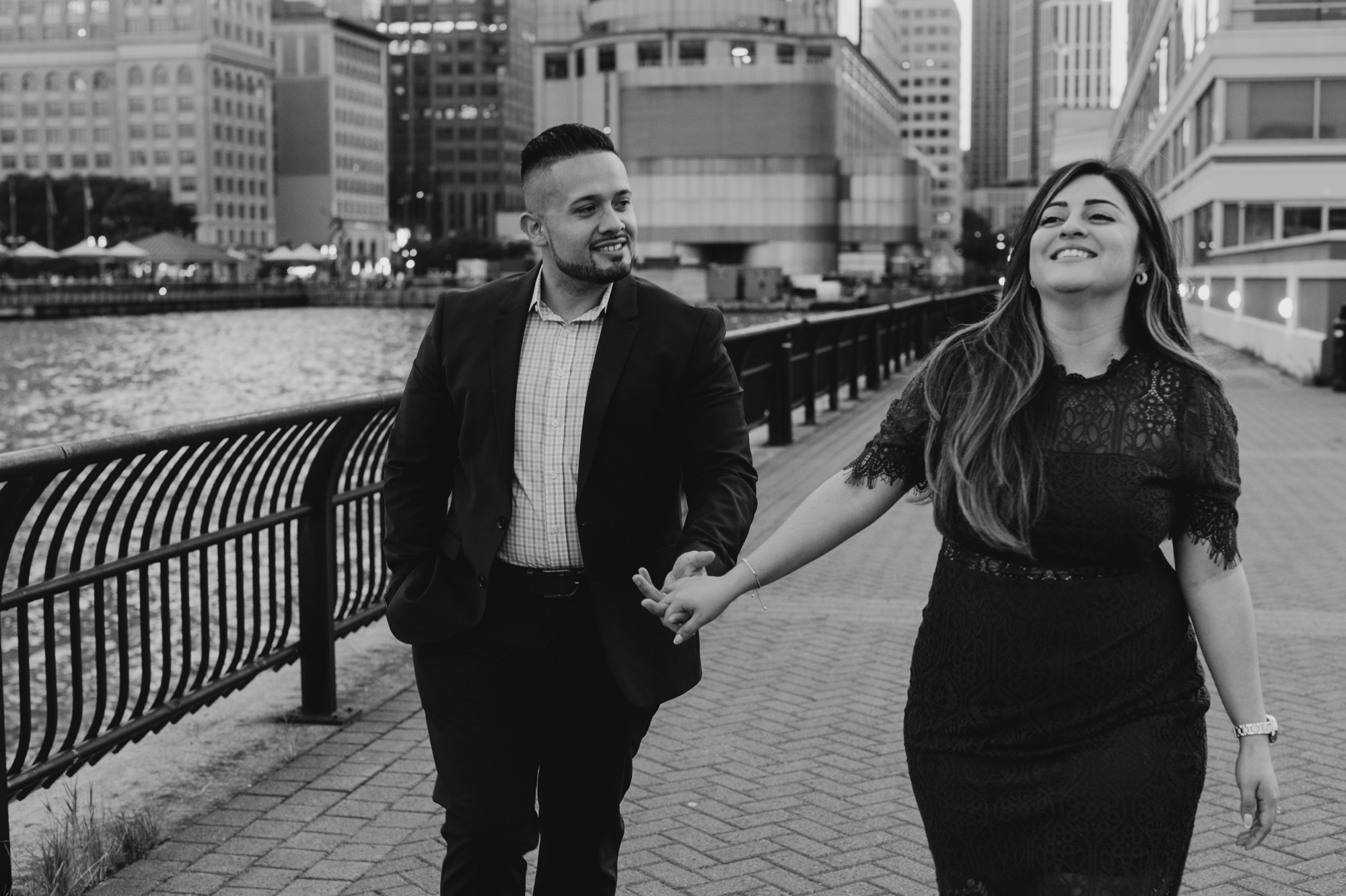 black and white image of a couple walking, holding hands and laughing