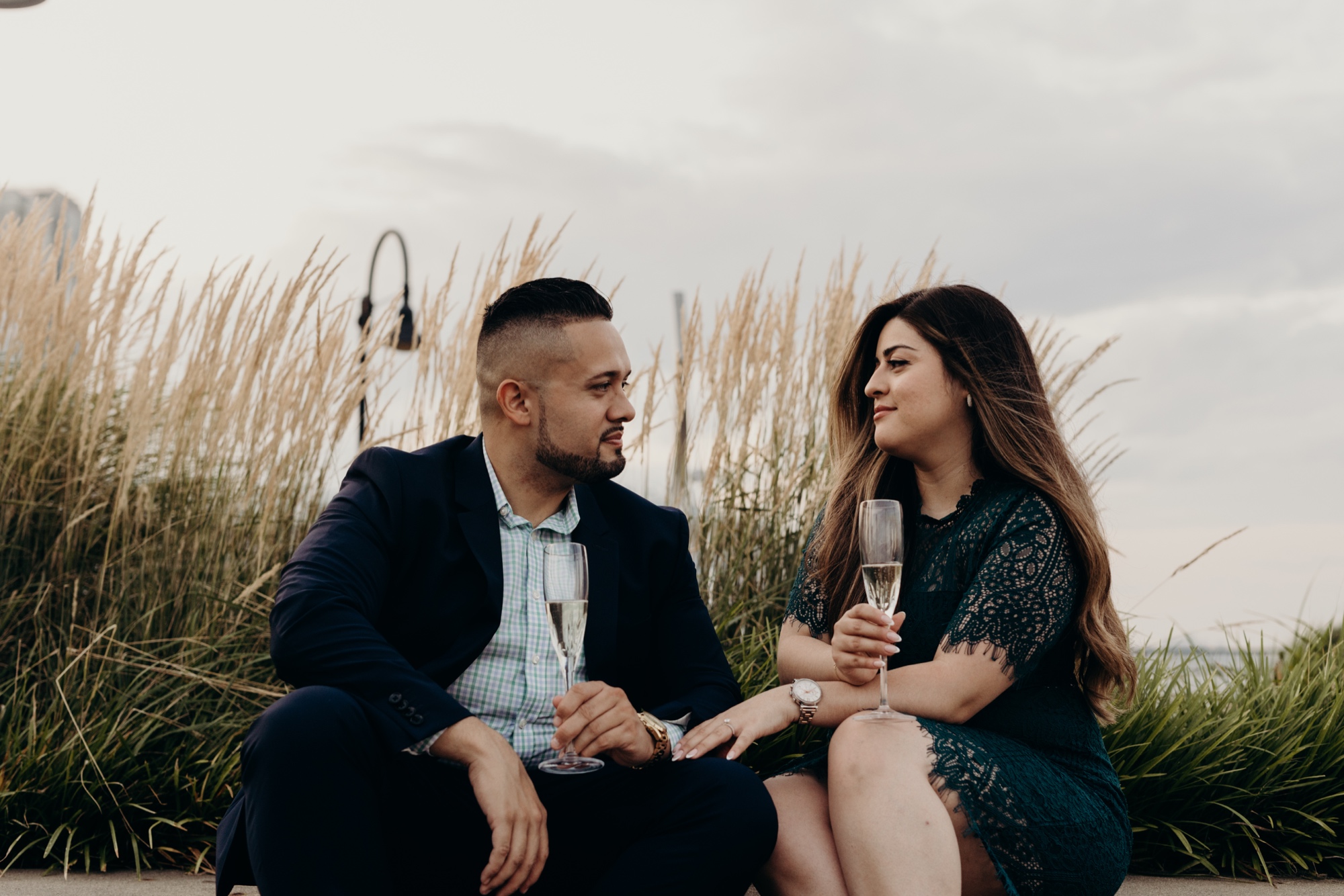couple sitting with champagne glasses in front of grass