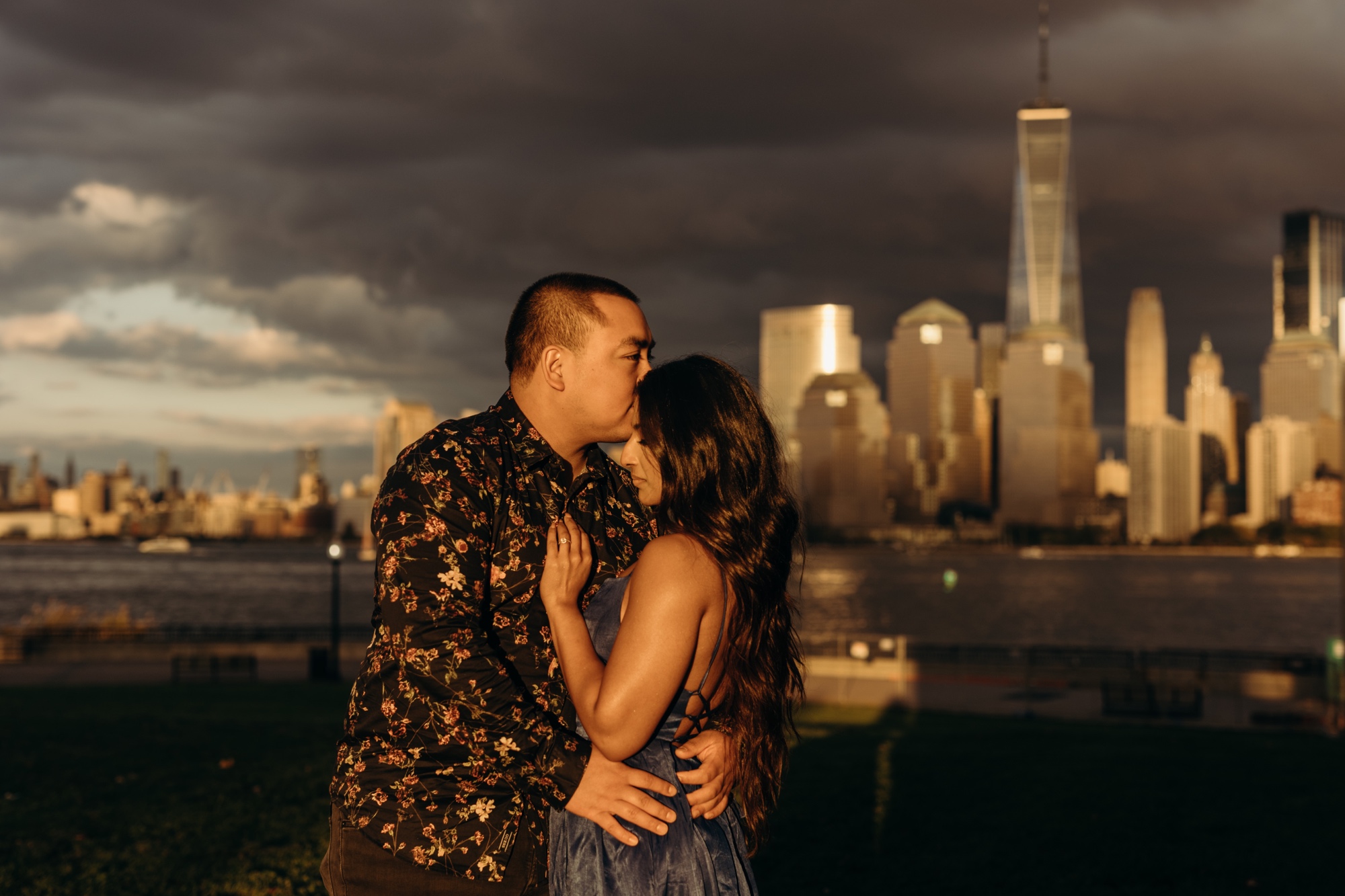 a couple hugs in front of the new york city skyline at sunset