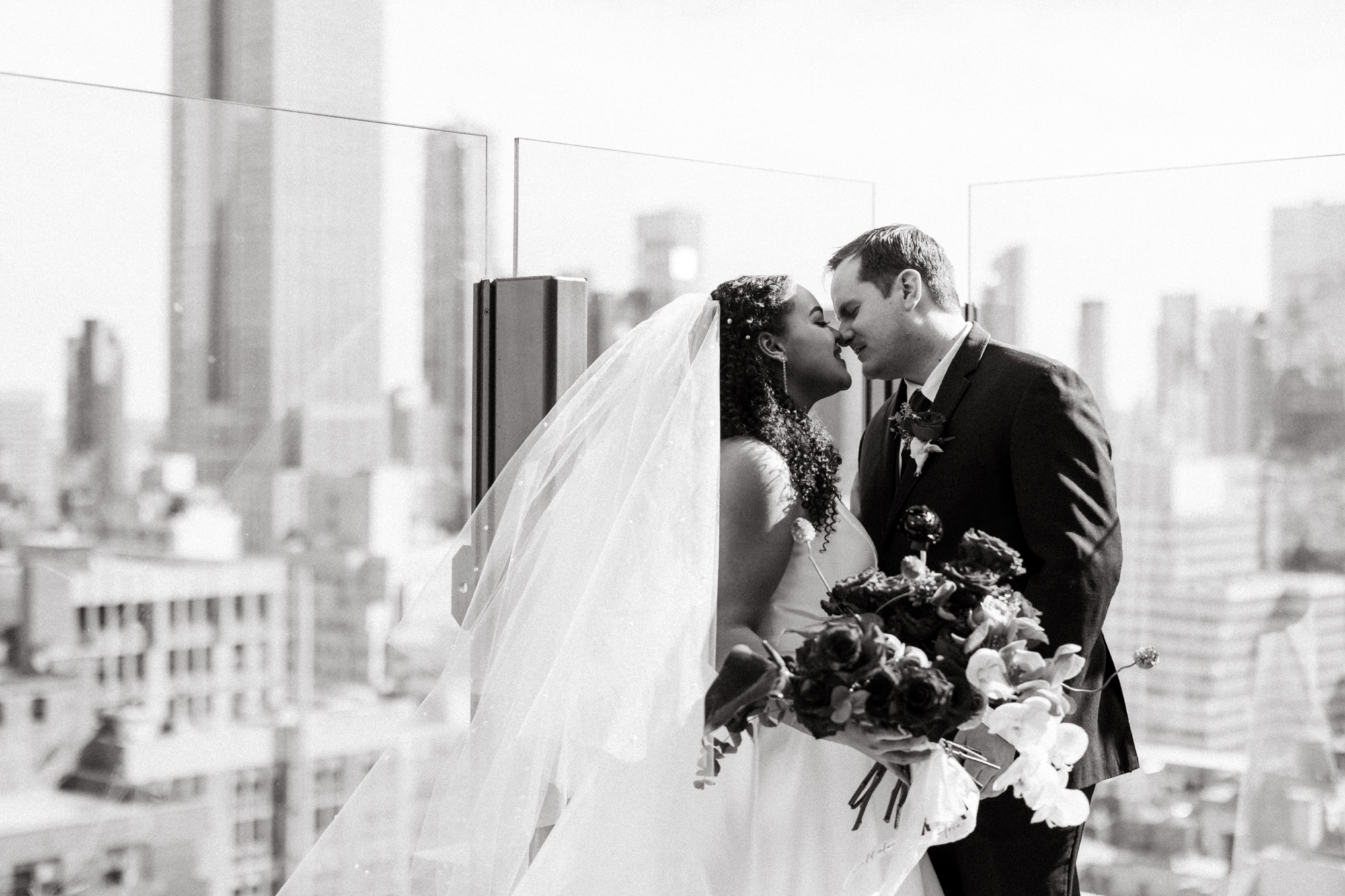black and white photo of bride and groom against nyc skyline