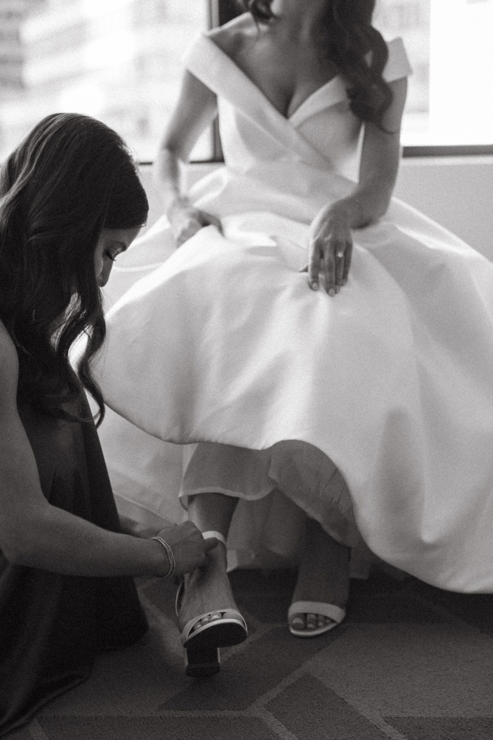 bridesmaid helping a bride put her shoes on