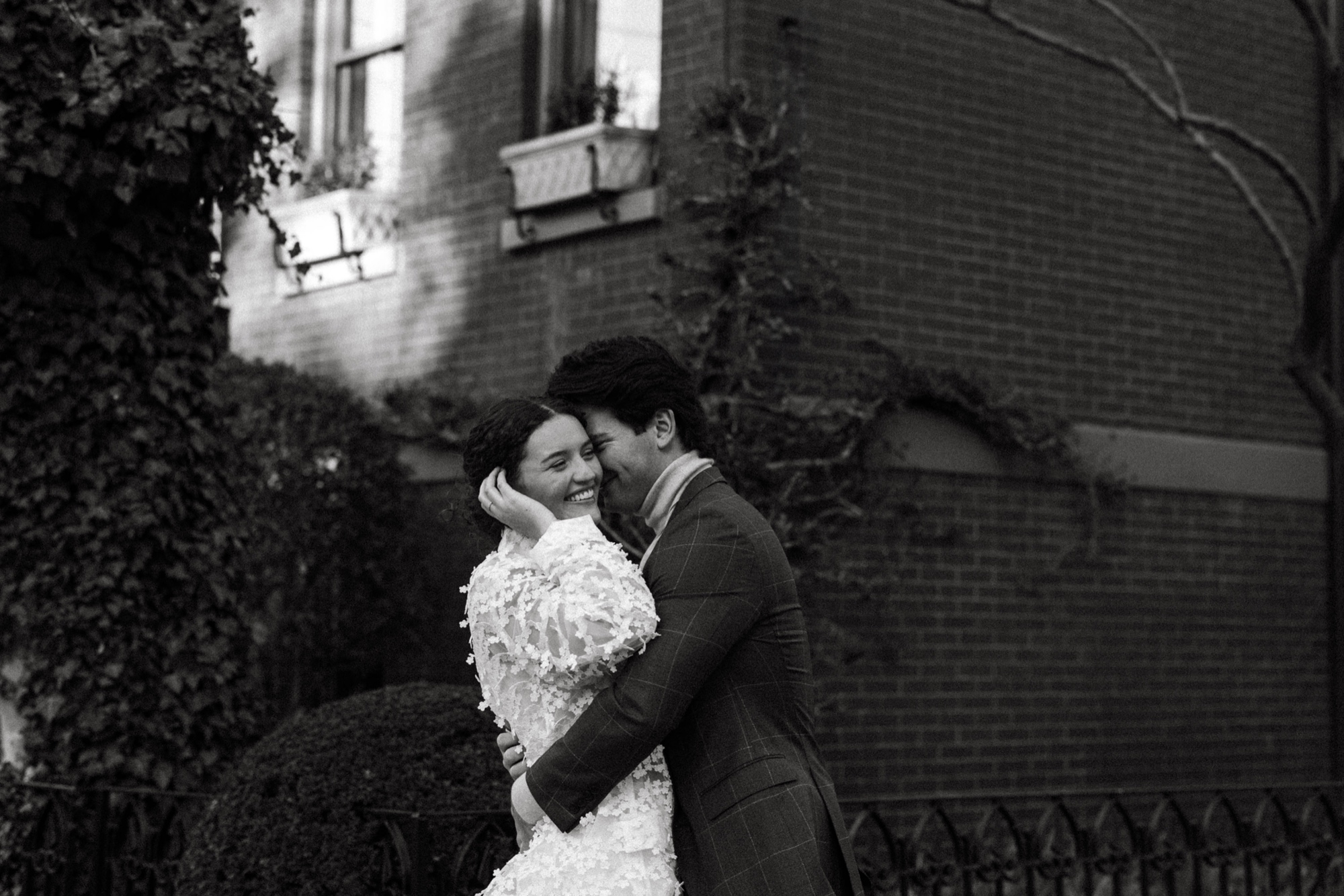 a black and white photo of a couple hugging on the corner in hoboken, new jersey