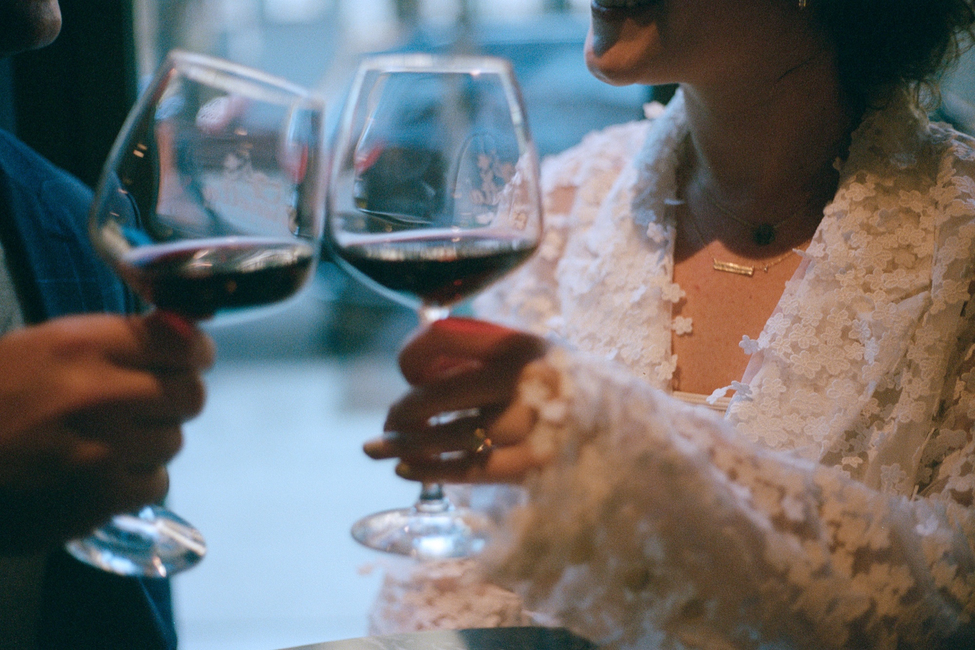 a film photo of a couple cheers-ing wine glasses