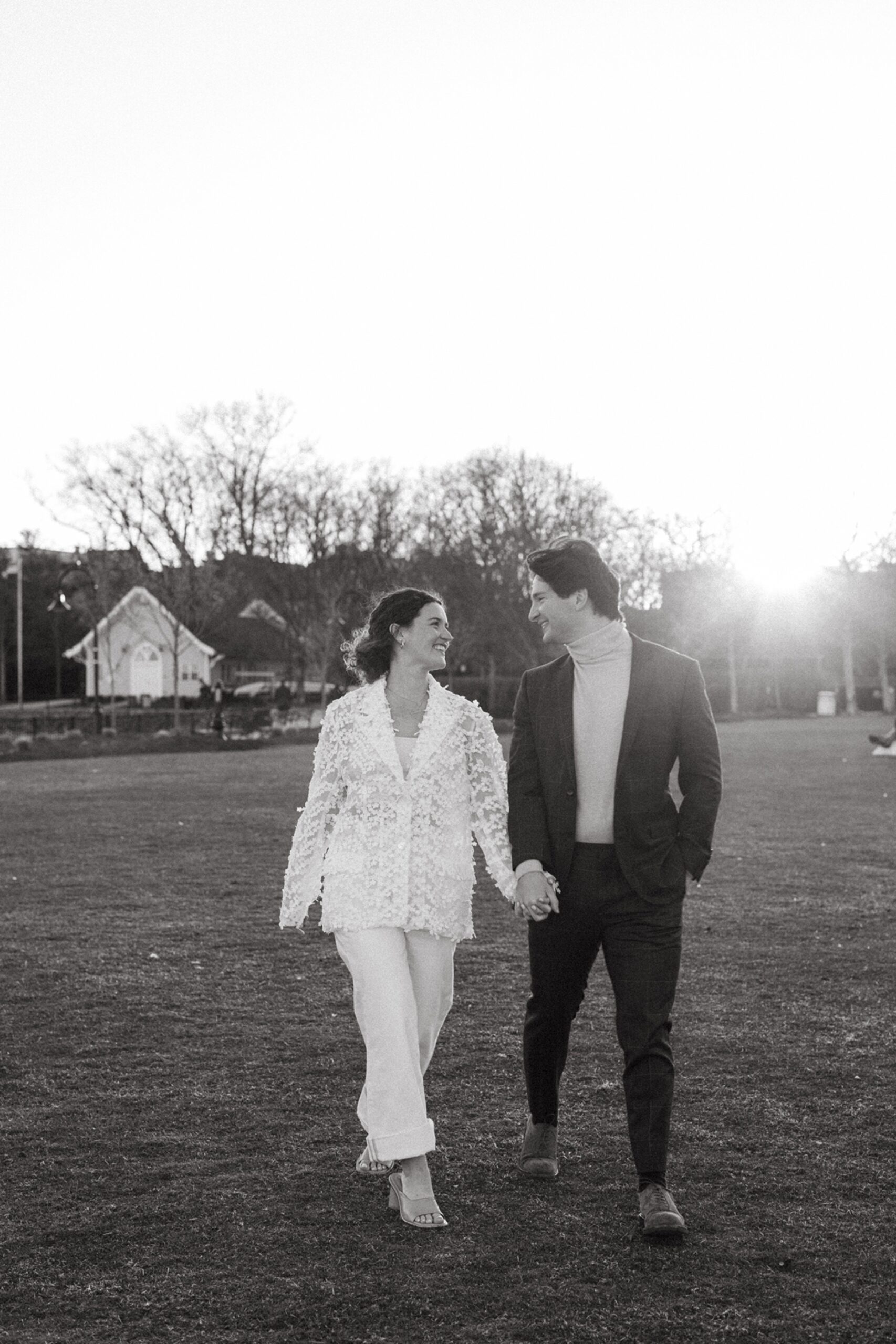 a black and white photo of a couple running in the grass in hoboken, new jersey