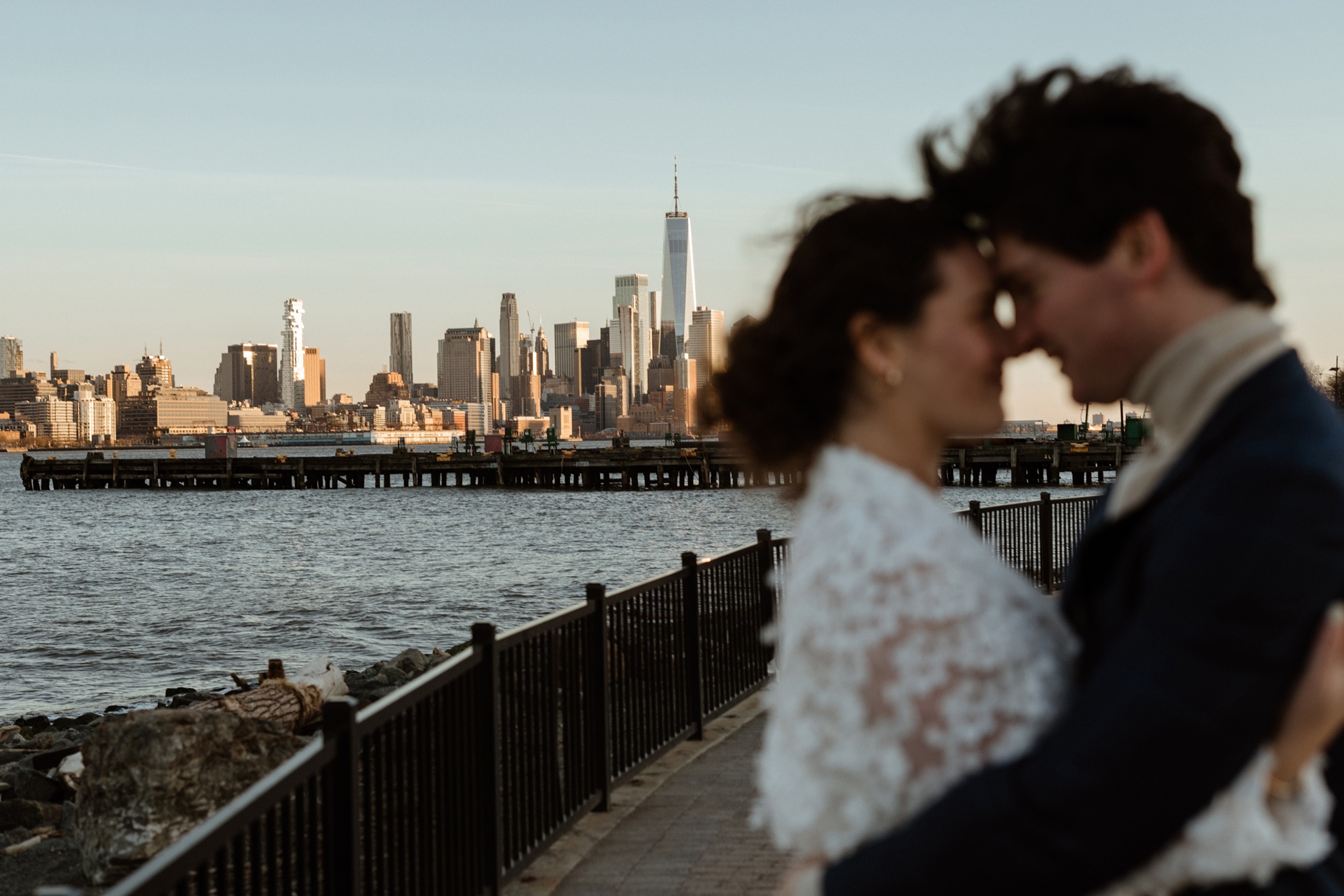 a couple touching foreheads out of focus with new york city skyline in the background